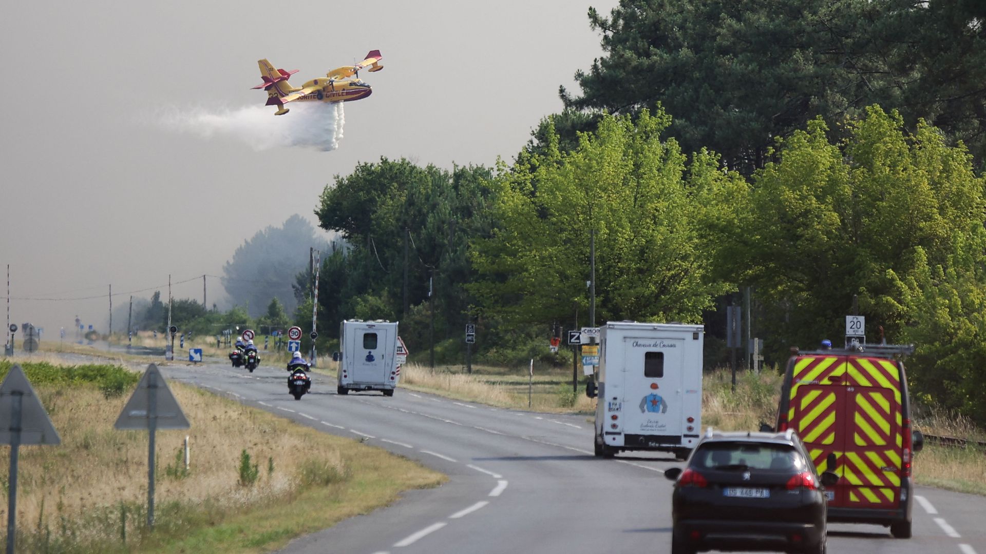 A plane drops water along a road while a fire threatens the evacuated town of Cazaux in La Teste-de-Buch, southwestern France, on July 14.