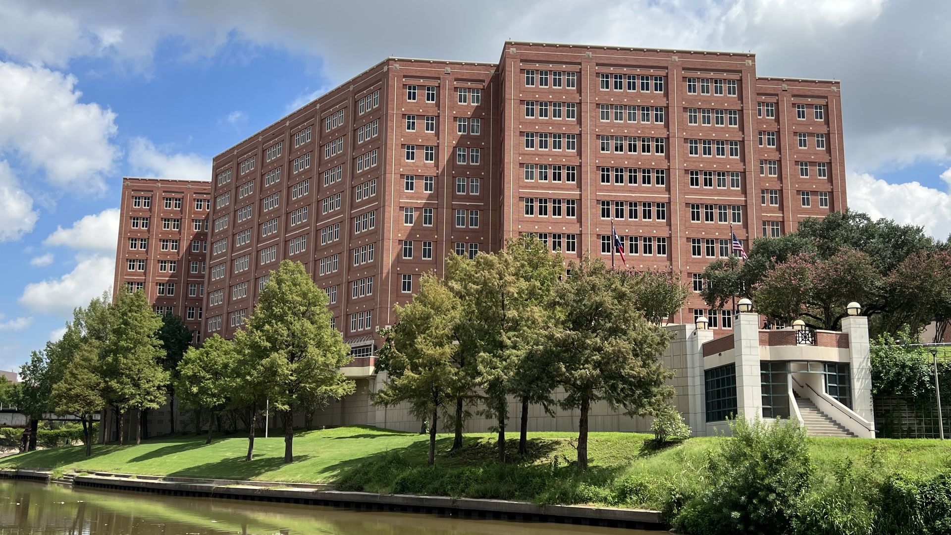 The Harris County Jail, a tall red-brick building with dark windows, sits on the banks of the Buffalo Bayou