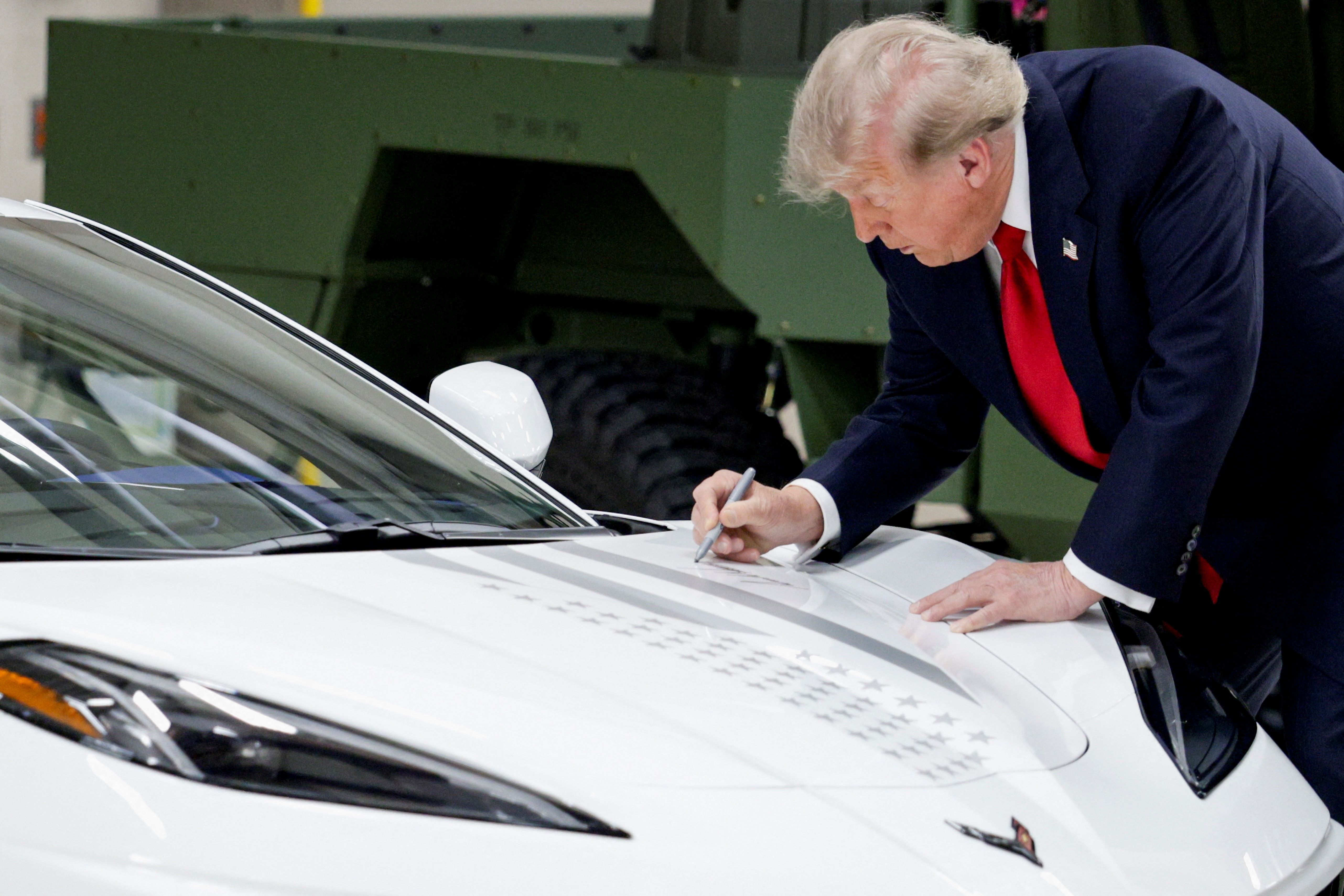 President Trump signs his autograph on a Corvette as he participates in a tour at the General Motors Milford Proving Ground in Milford, Michigan, yesterday.