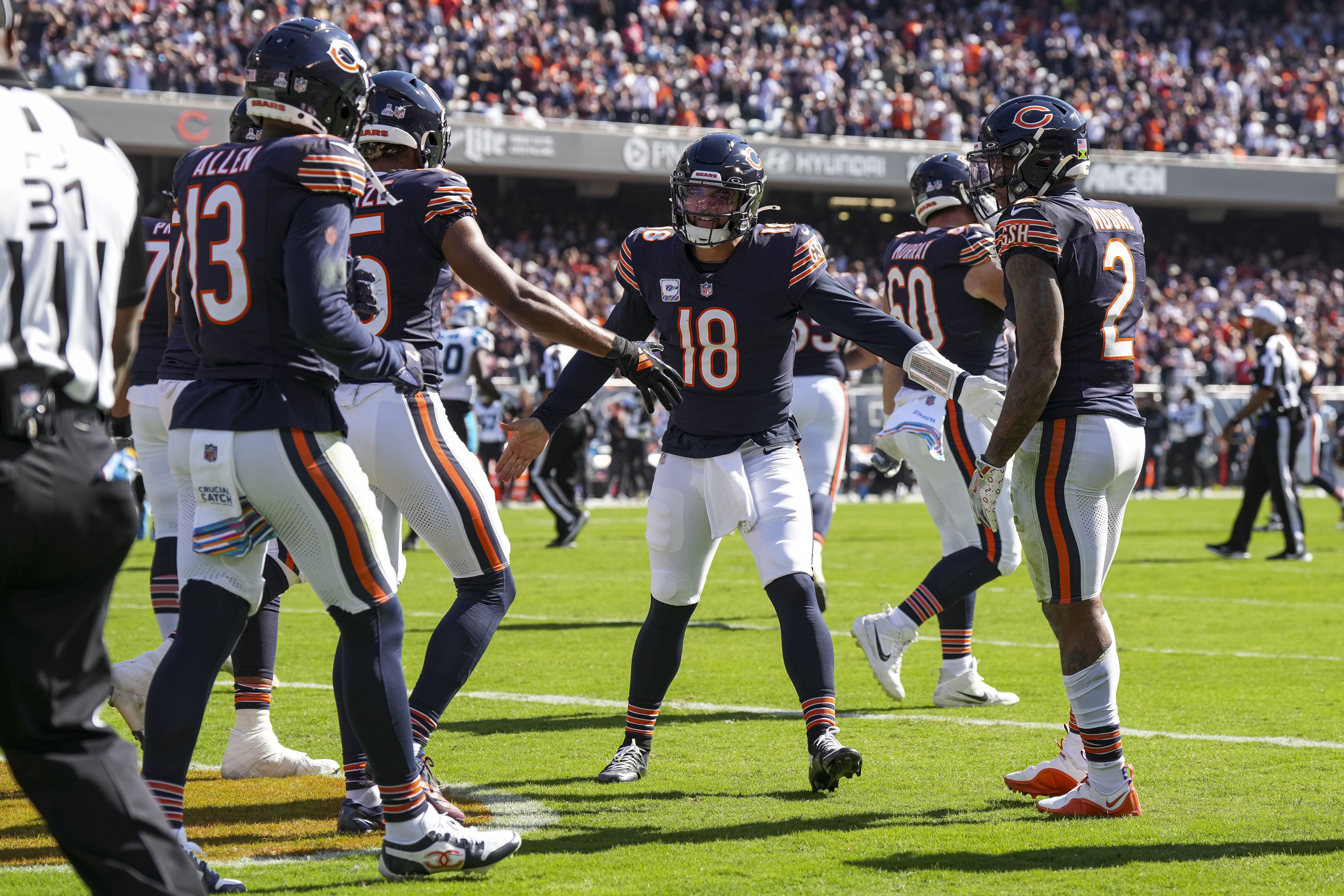 Photo of football players congratulating themselves on a field inside a stadium. 