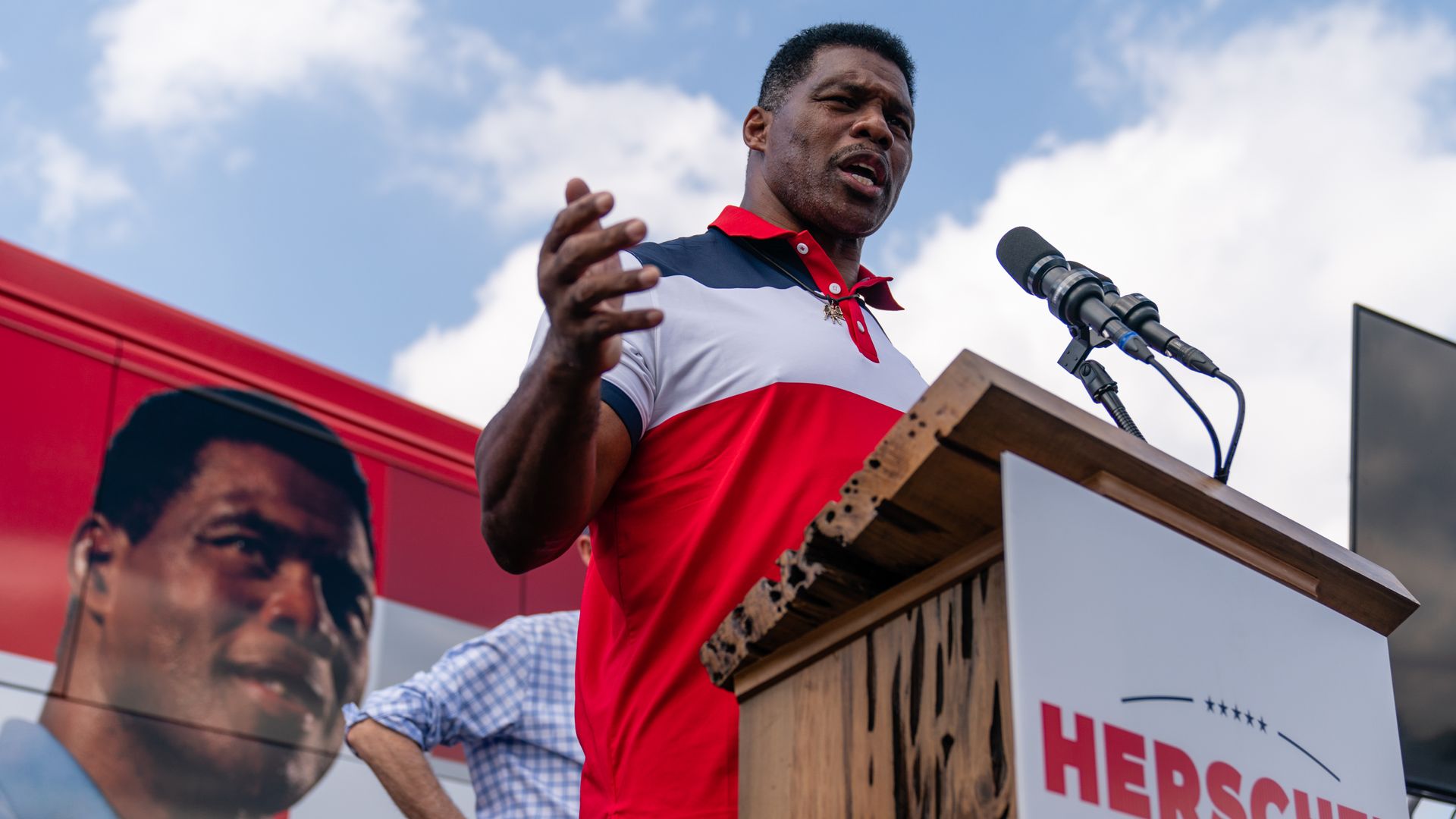 Photo of Herschel Walker speaking from a podium at a campaign stop