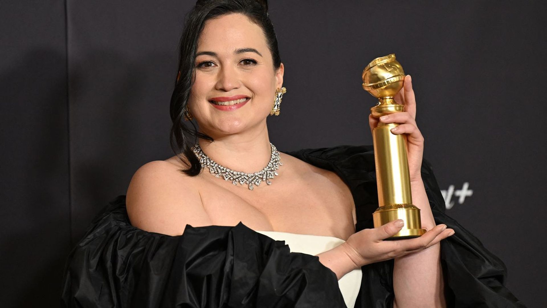 photo of a woman holding up a Golden Globe