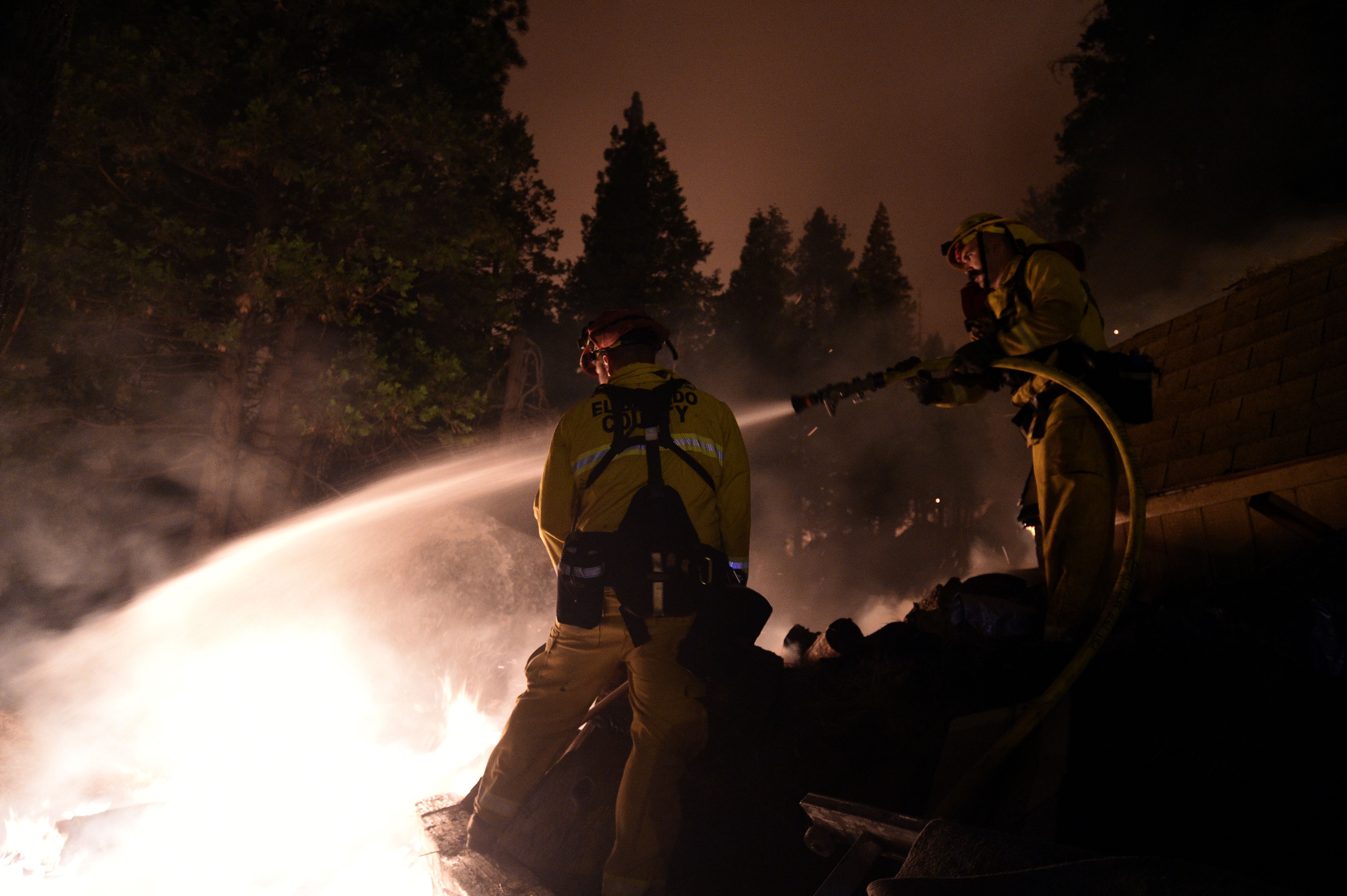 Firemen attempt to extinguish a fire as the Caldor Fire approaches residential areas. 