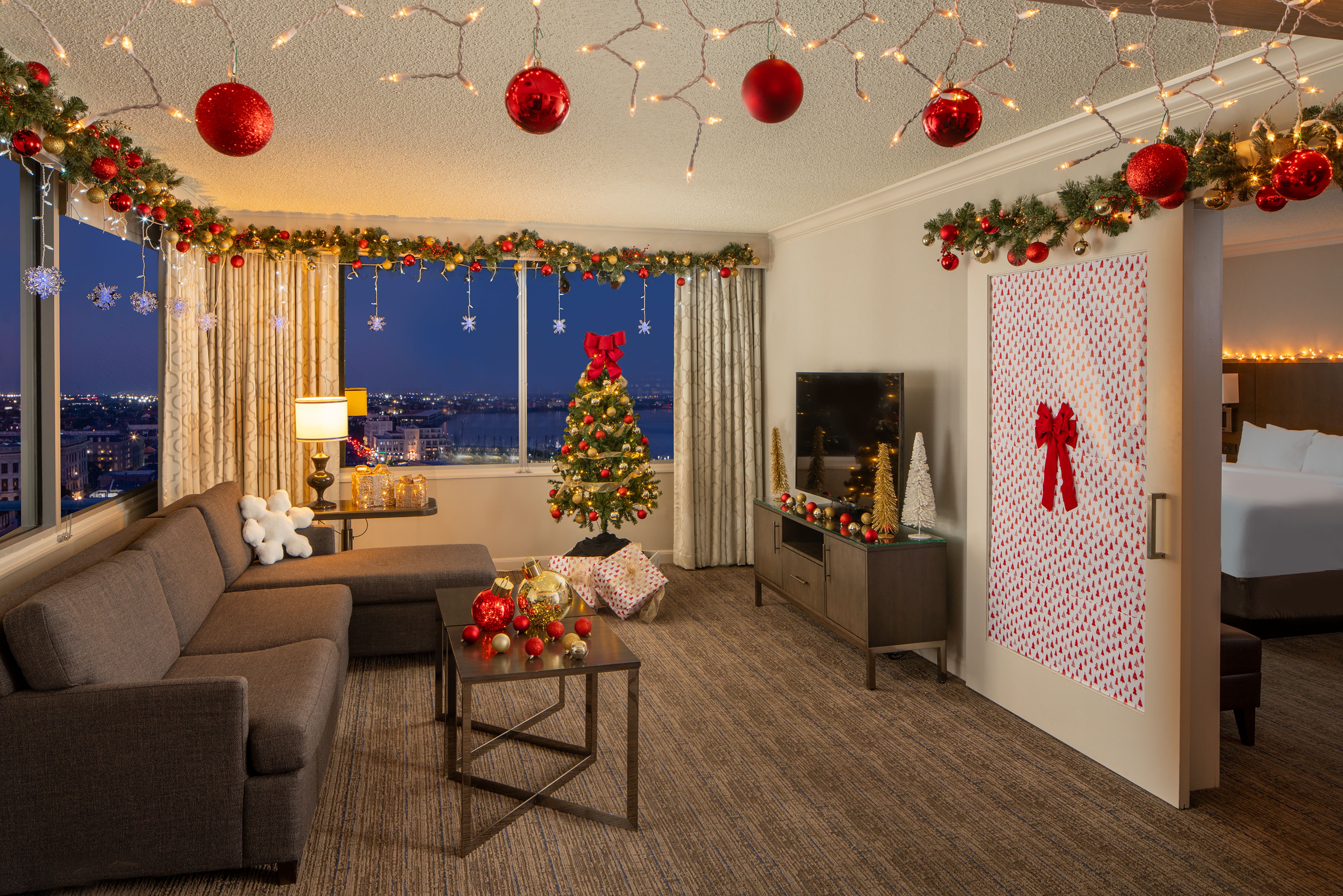A hotel room that's been decorated for Christmas with garlands and lights and a tree.