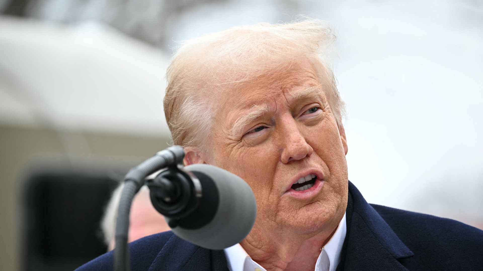 A close-up shot of Donald Trump speaking into a microphone