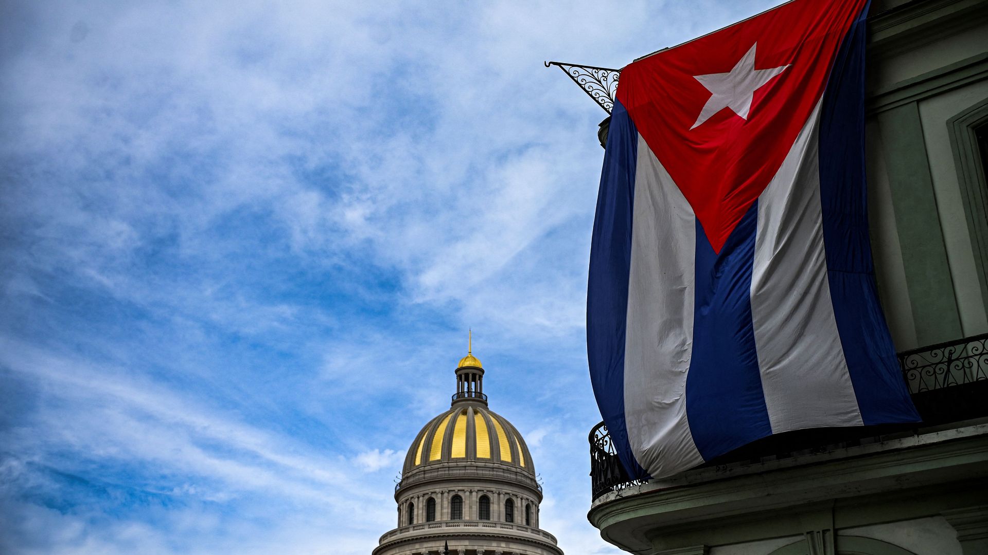 Photo of the Cuban capitol building with a large Cuban flag hanging in the foreground