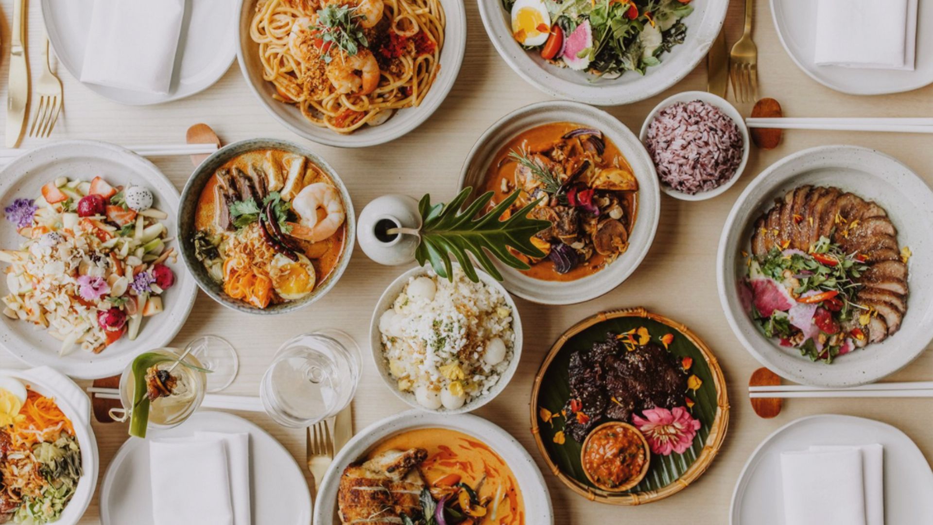 an assortment of colorful food in white bowls on a white tablecloth