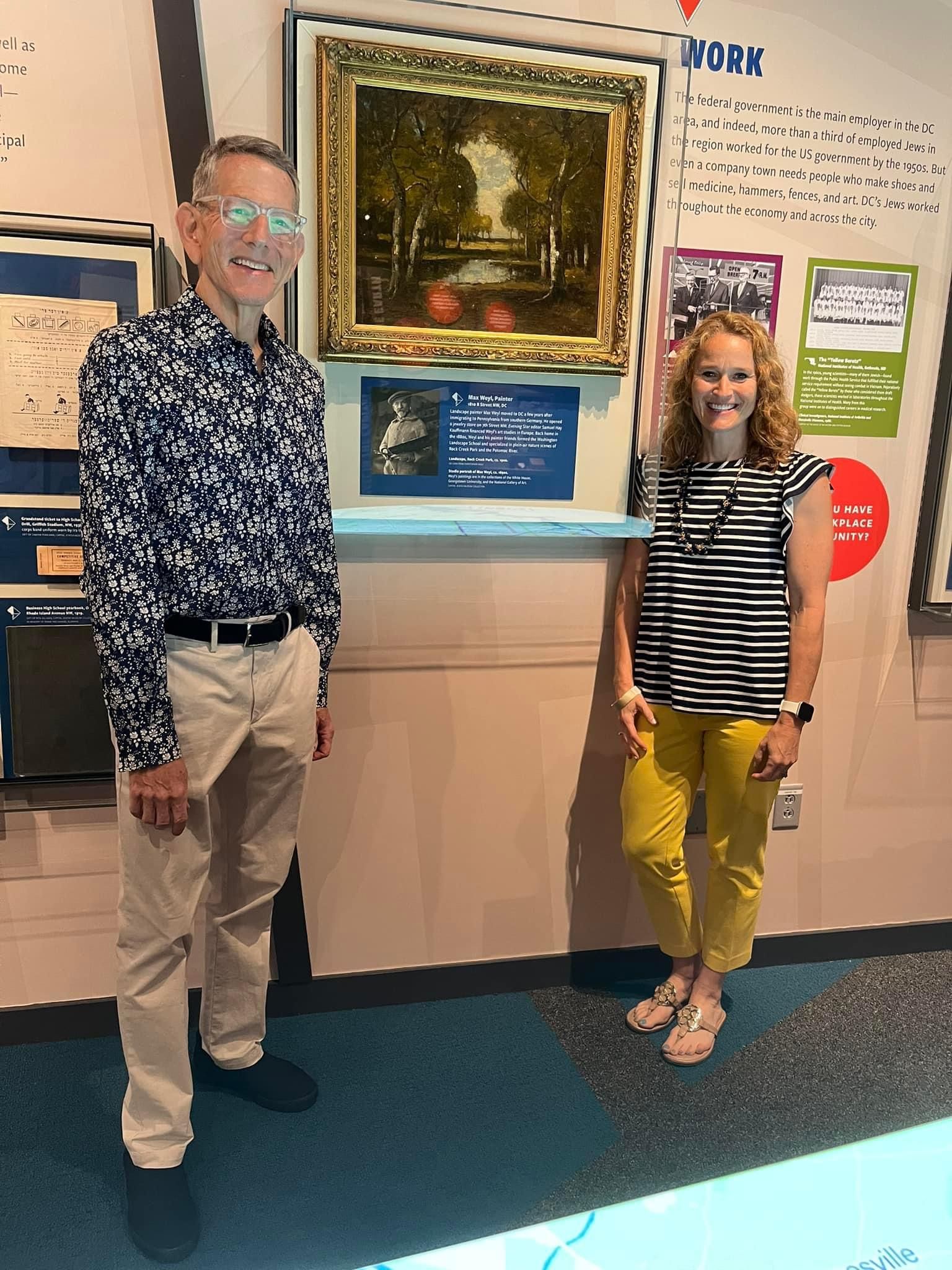 two people standing in front of a painting