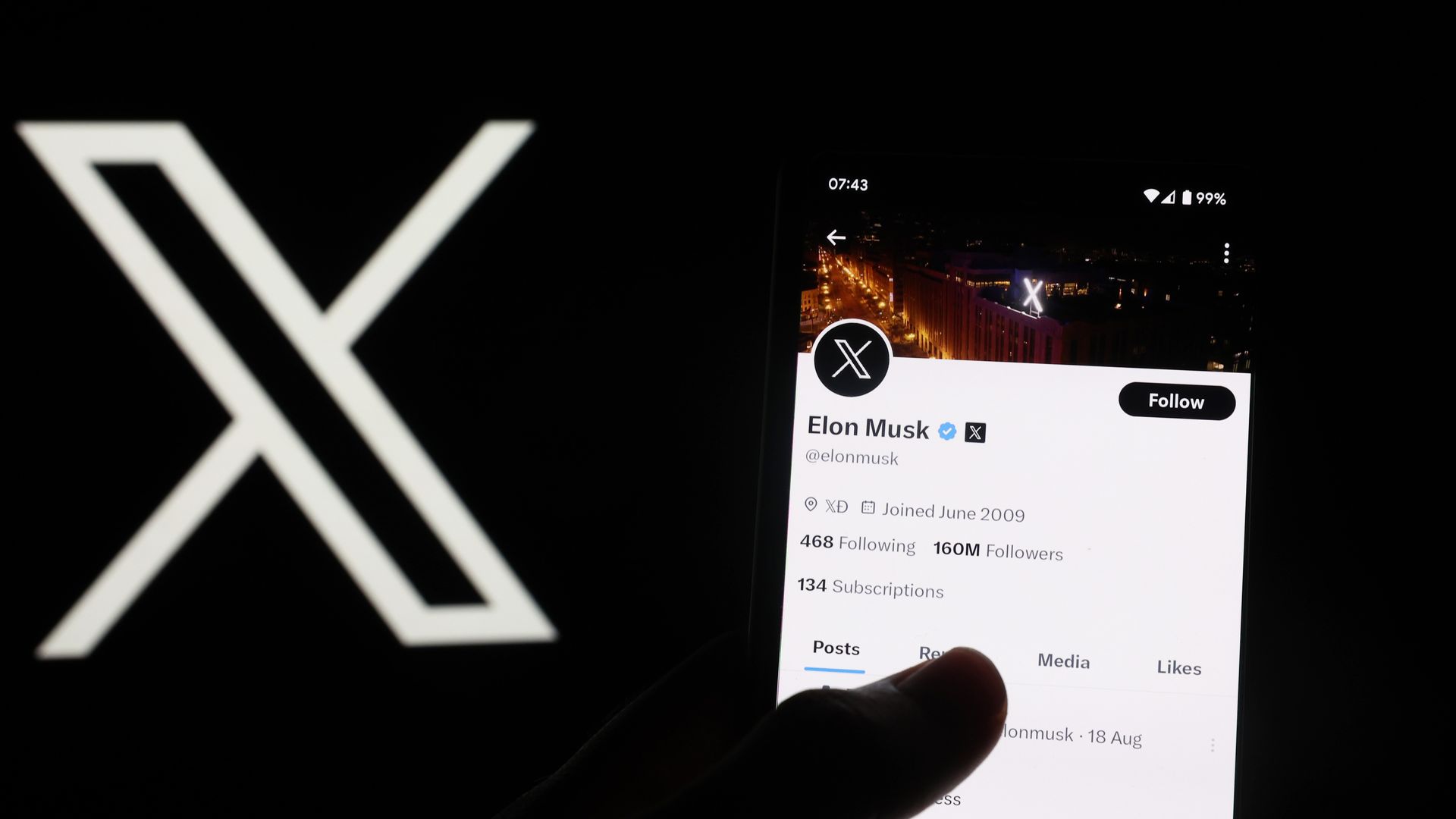 Elon Musk's X profile seen on a phone in front of the X logo
