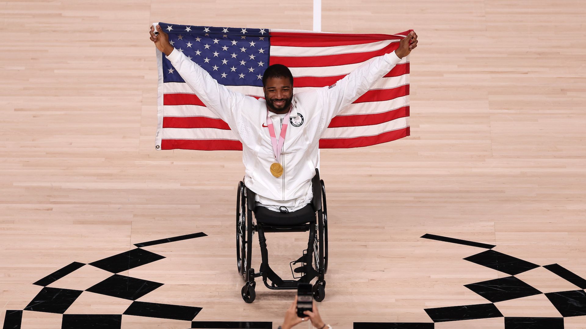 Wheelchair basketball paralympian Trevon Jenifer holds an American flag on the court