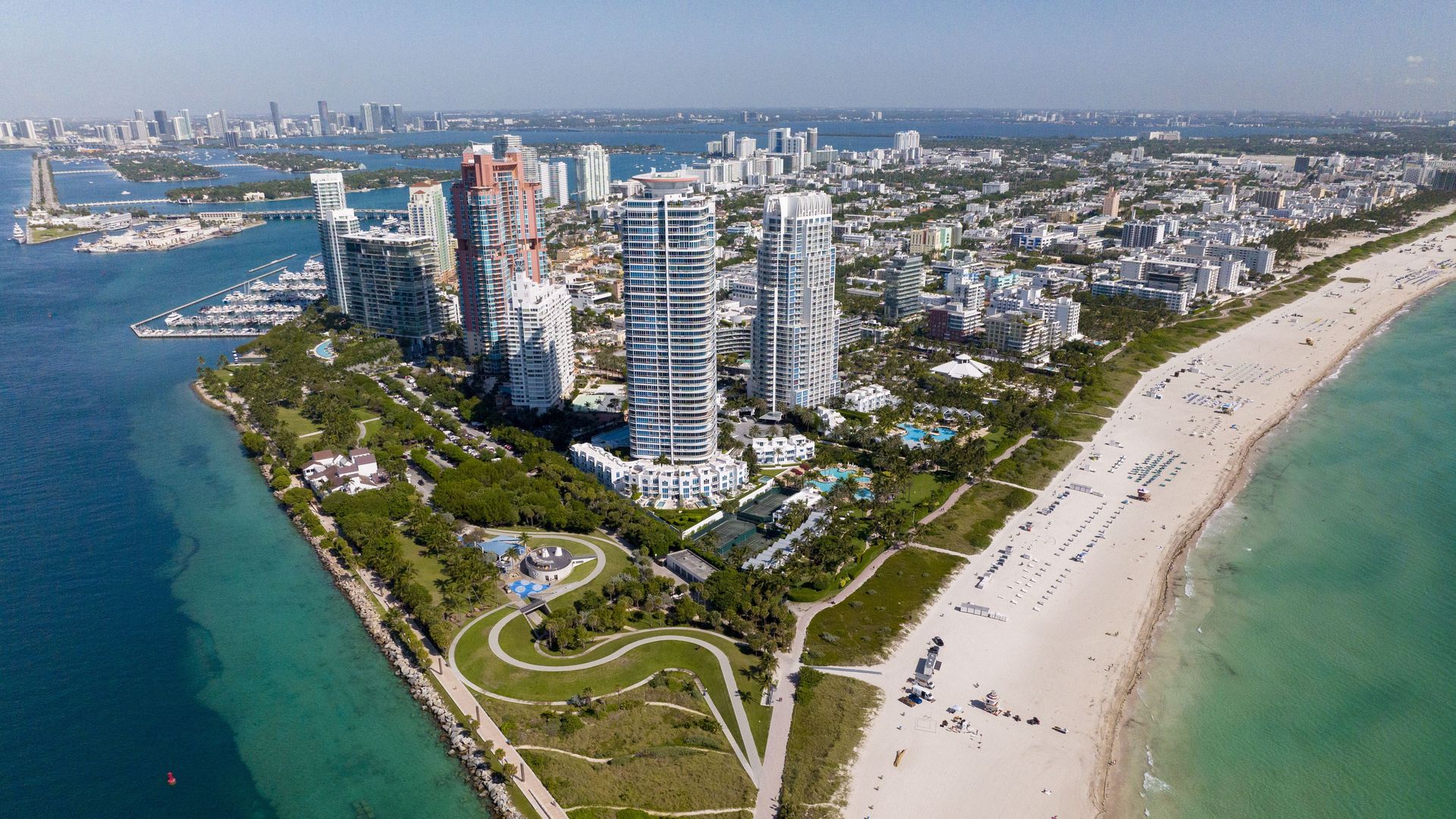 An aerial image shows a park and tall condominiums, as seen from a drone in the sky. 