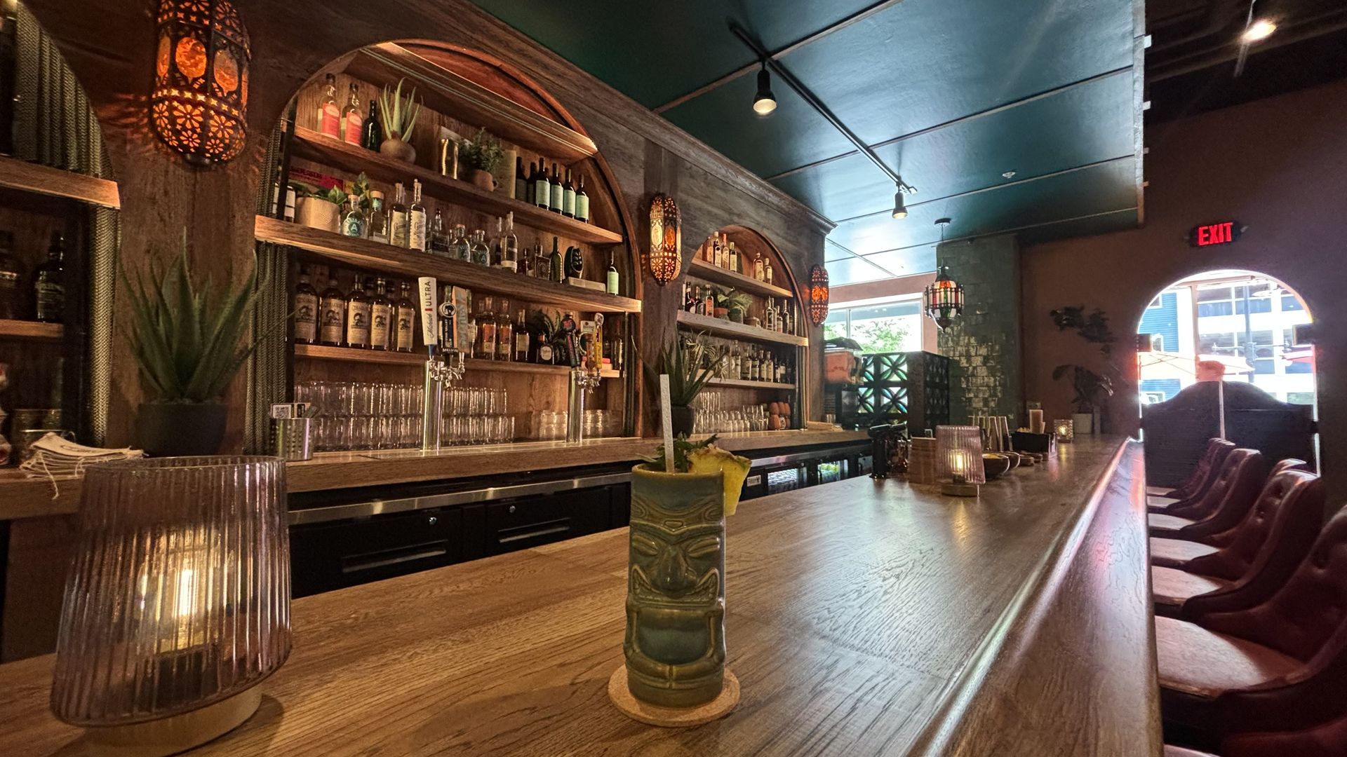 A tiki cocktail with a pineapple sits on the bar.