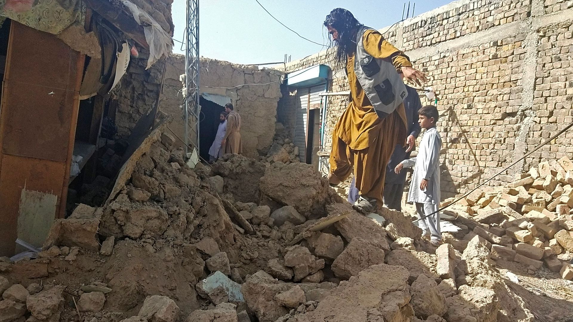  Residents gather next to the debris of their houses that collapsed following an earthquake in the remote mountainous district of Harnai on October 7.