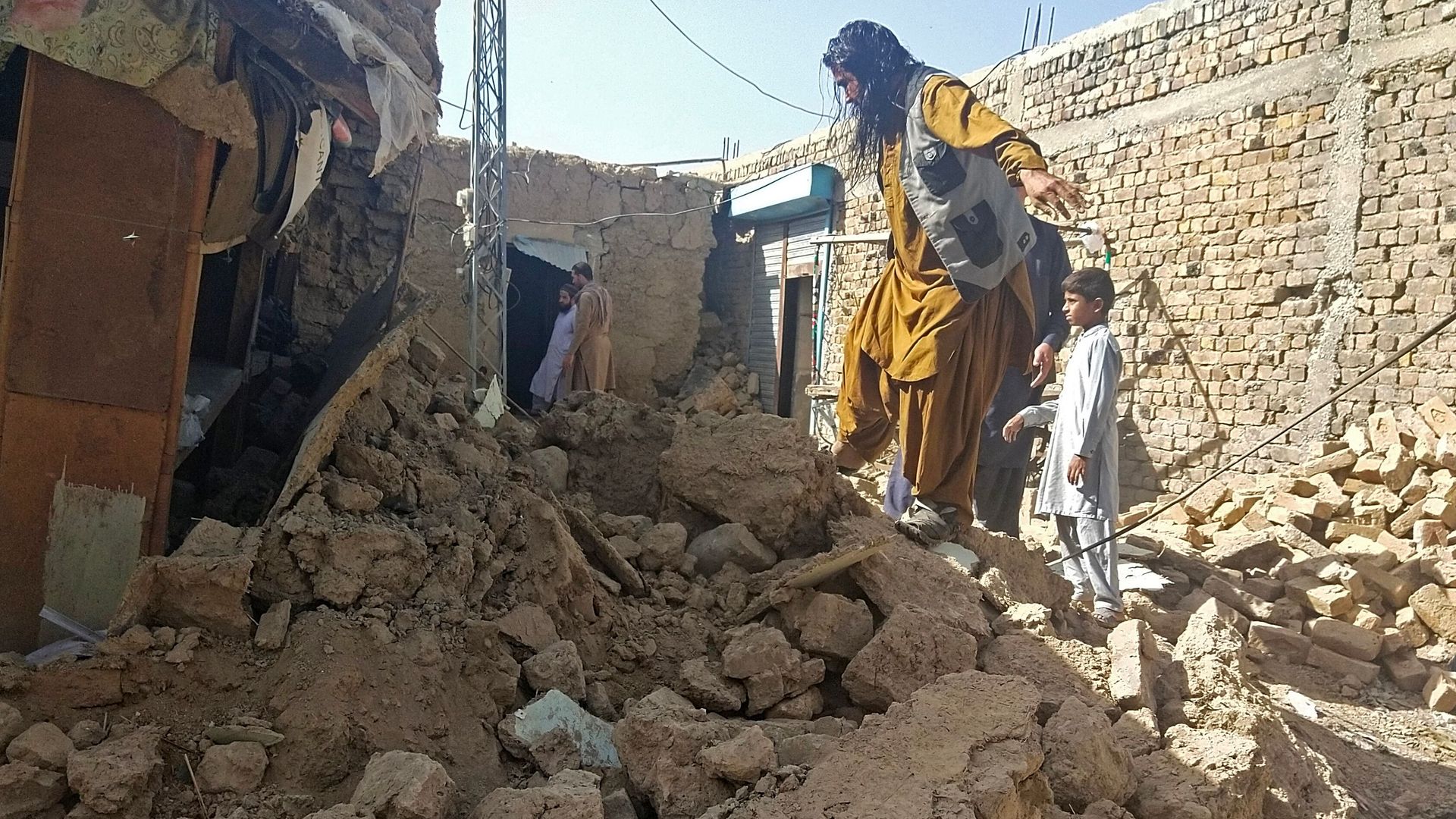 Residents gather next to the debris of their houses that collapsed following an earthquake in the remote mountainous district of Harnai on October 7.