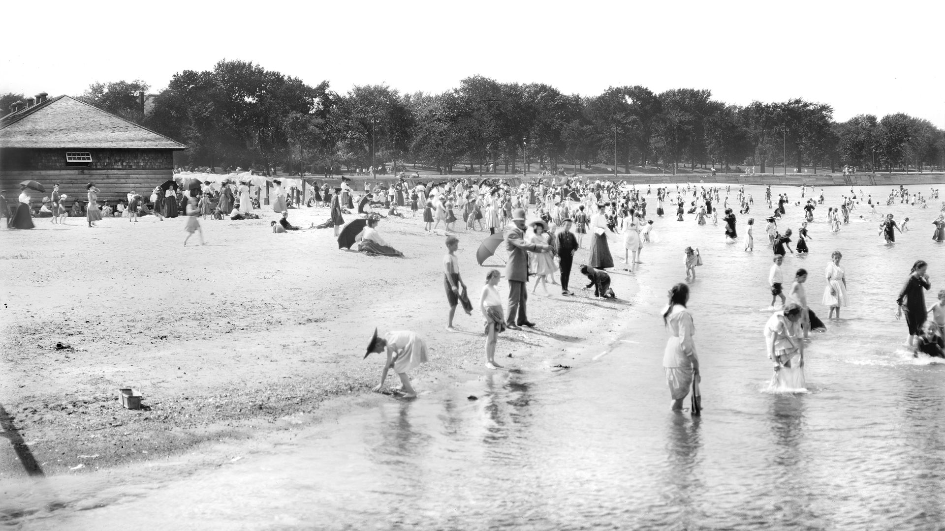 Photo of people wading in water at a beach. 