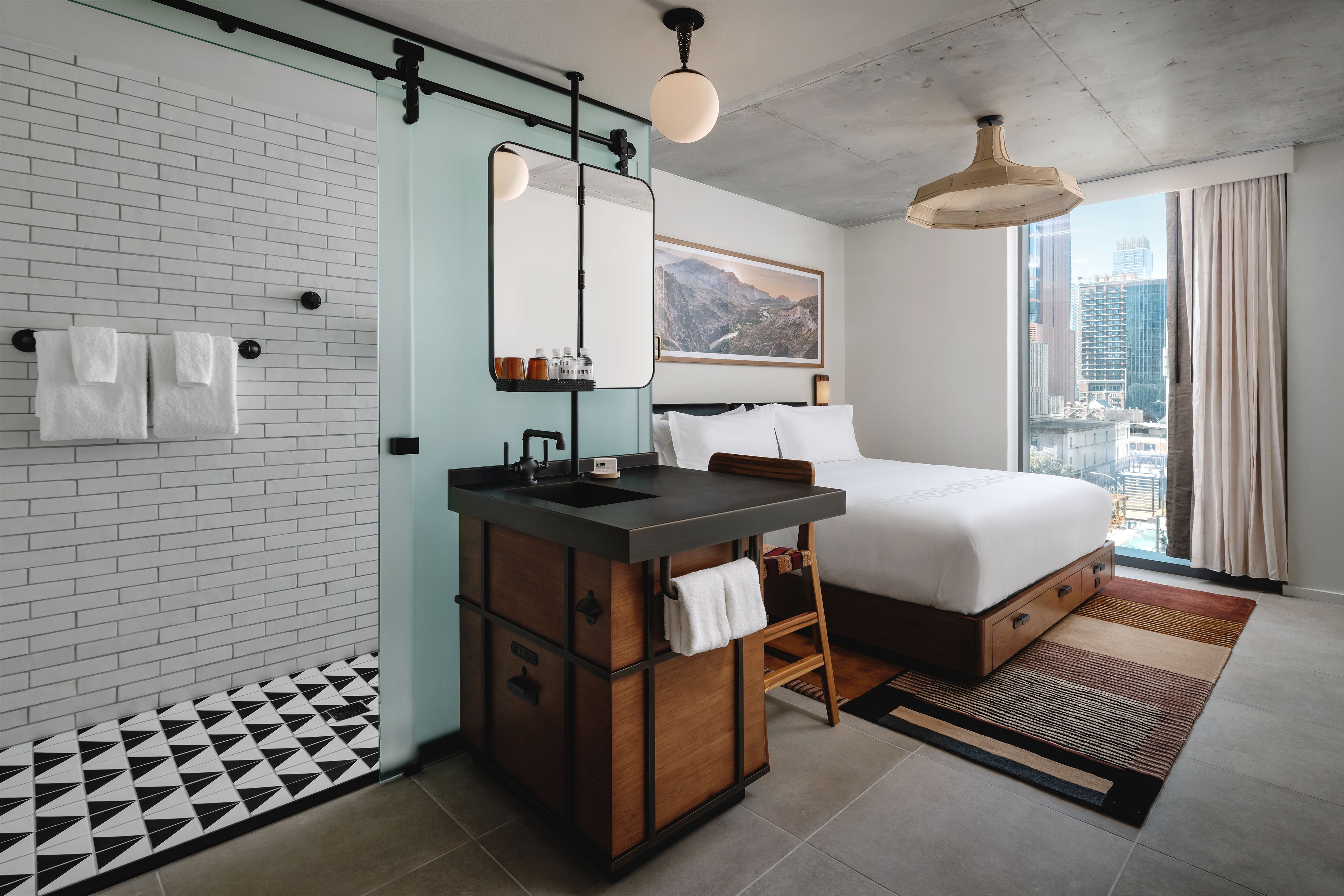 Ein Foto eines Hotelzimmers mit einem Waschbecken im Vordergrund und einem Bett im Hintergrund.