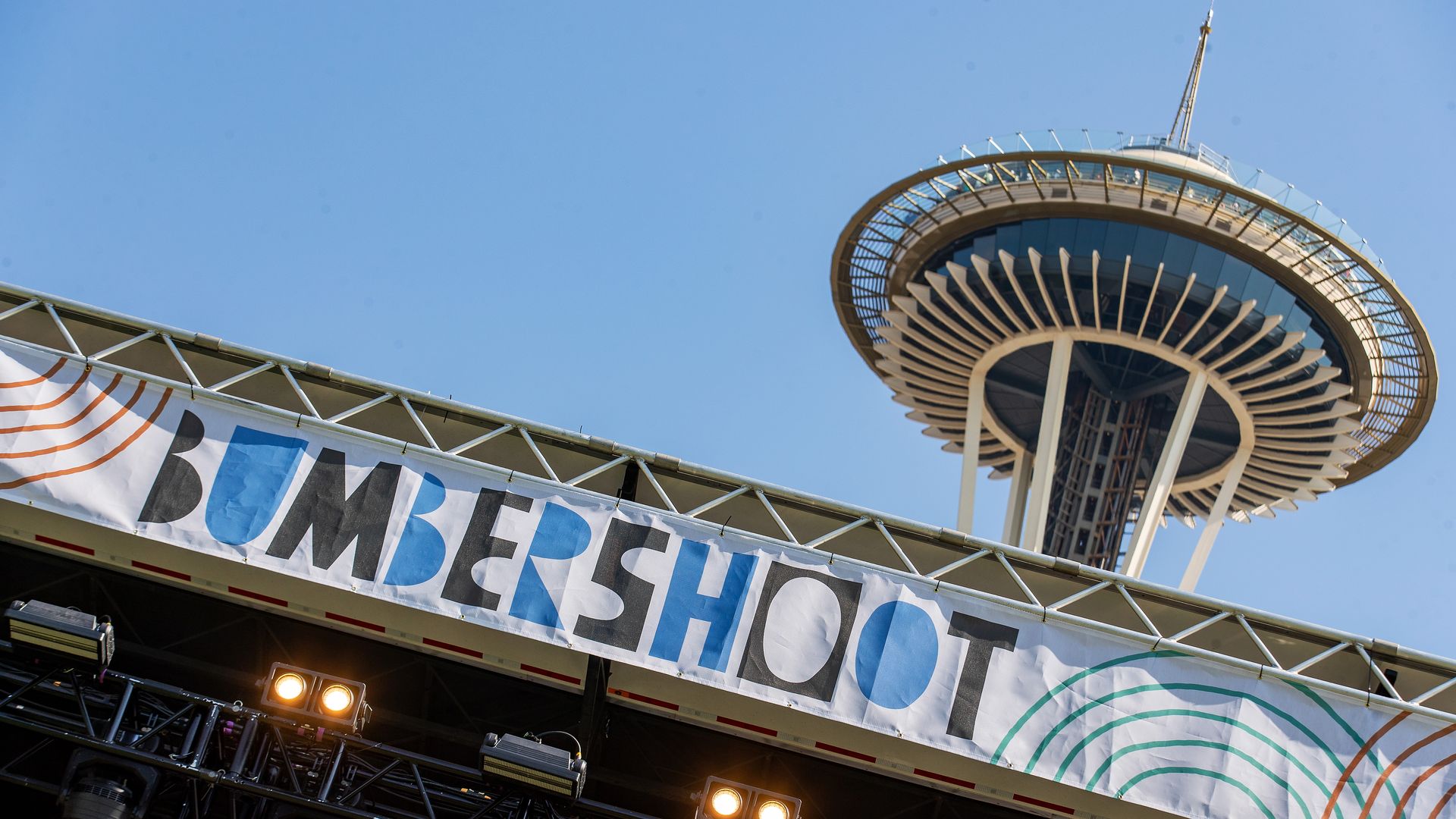 A banner reading "Bumbershoot" is hung at the top of a stage with the Space Needle in the background.