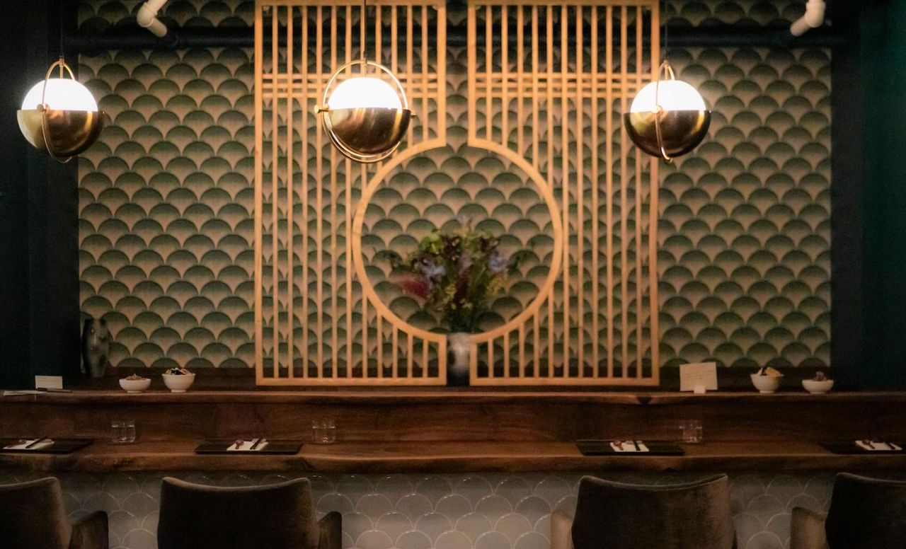 A photo showing a dining room with Art Deco features brass fixtures and a chefs counter dining space.