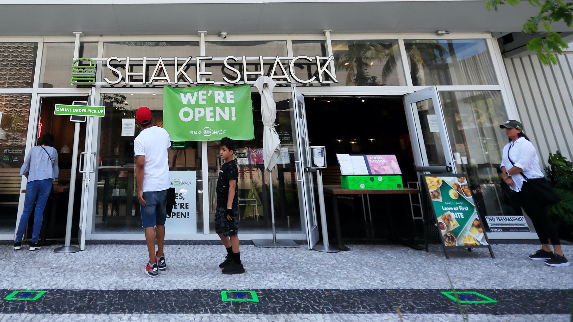 Customers wait for to-go orders outside Shake Shack in South Beach on April 19, 2020 in Miami Beach