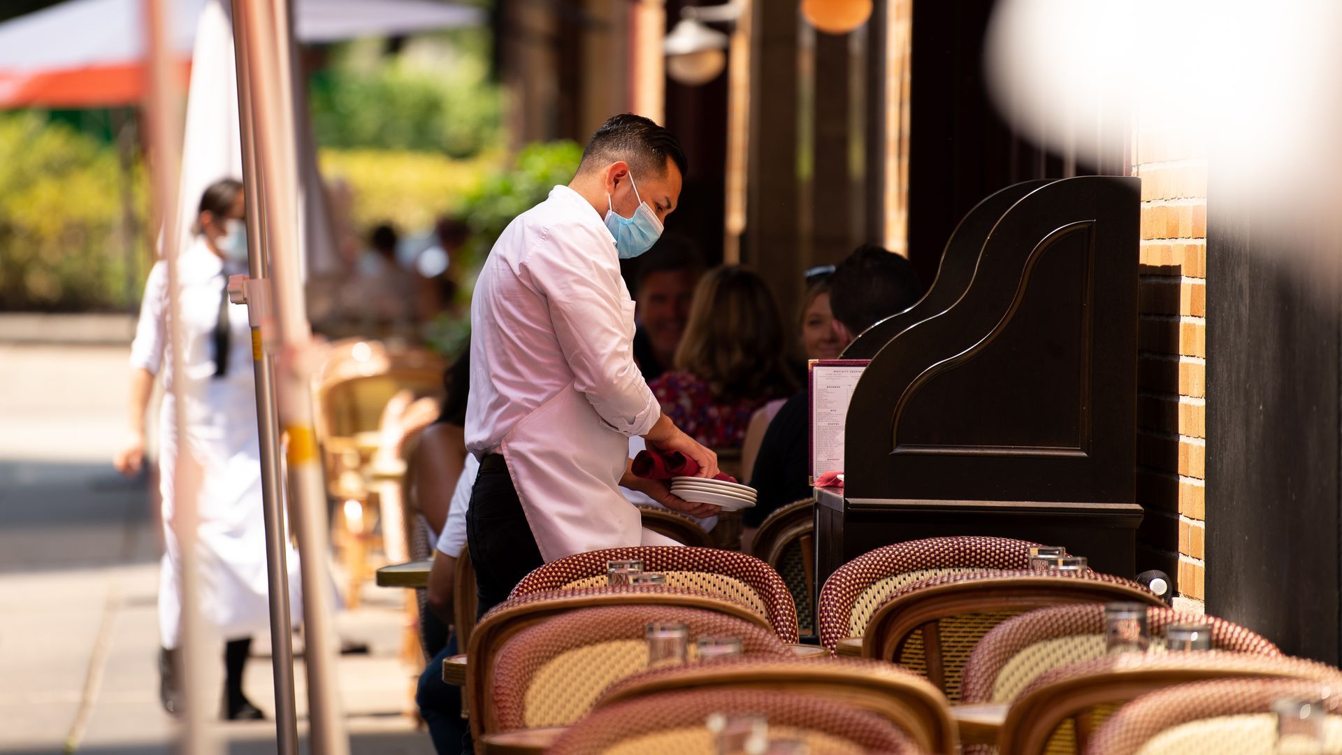 A server wears a protective mask in the outdoor dining section of a restaurant in Philadelphia.