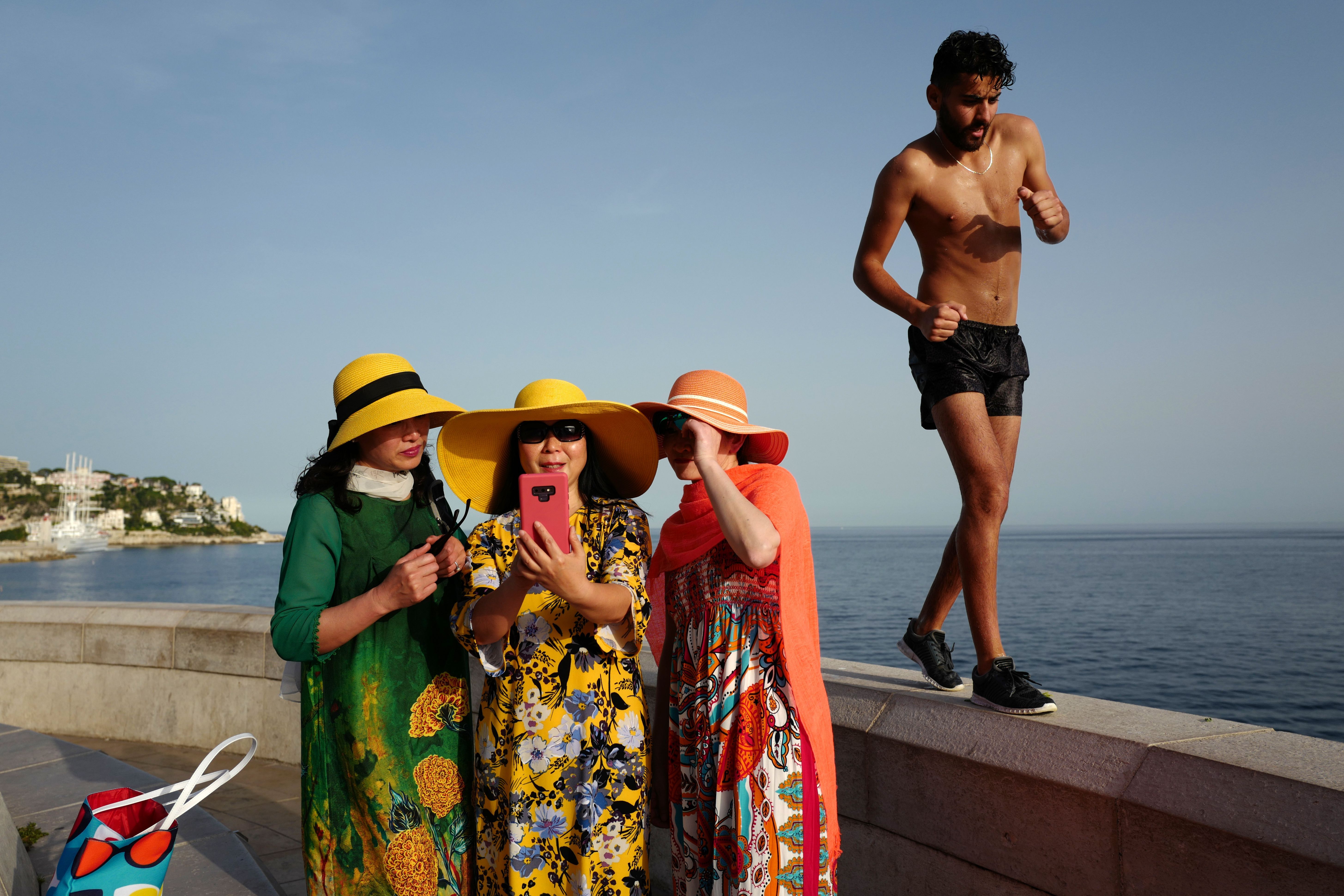 A man walks by as tourists take selfies on the French Riviera city of Nice on June 24.