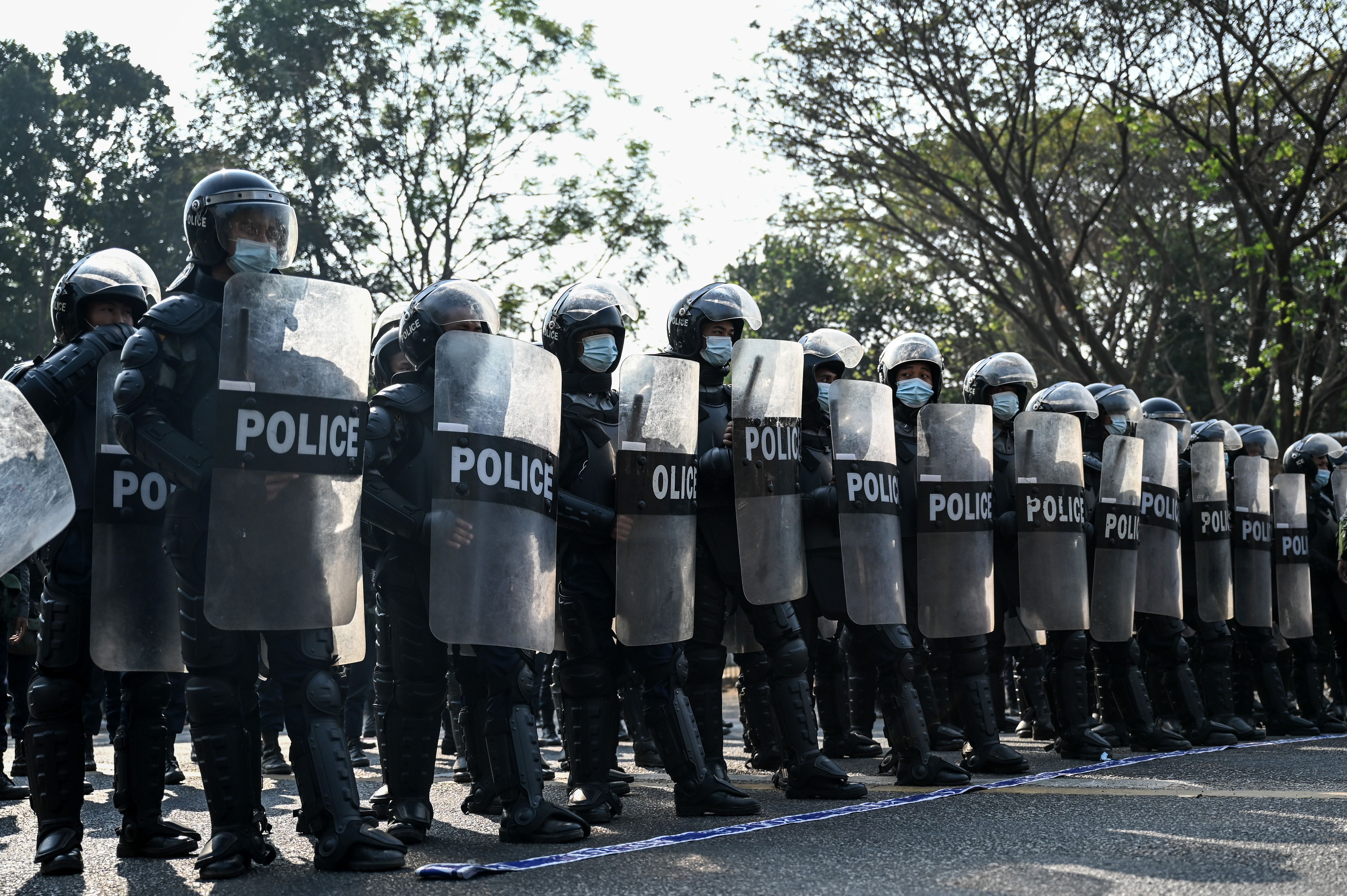 Riot police block the street as protesters hold a demonstration against the military coup in Yangon on February 7
