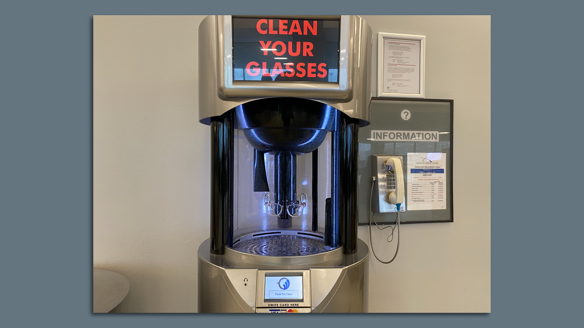 A tall, silver machine for cleaning glasses in a hallway of Terminal A of Houston's airport.