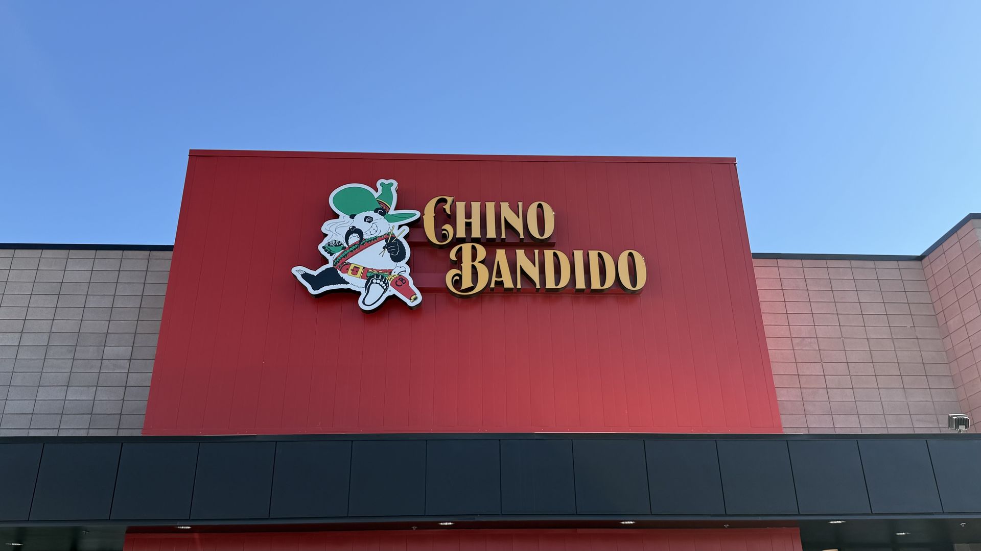 Sign on a building with a red background reading "Chino Bandido" in yellow letters next to a cartoon panda wearing a green sombrero and a bandolier.