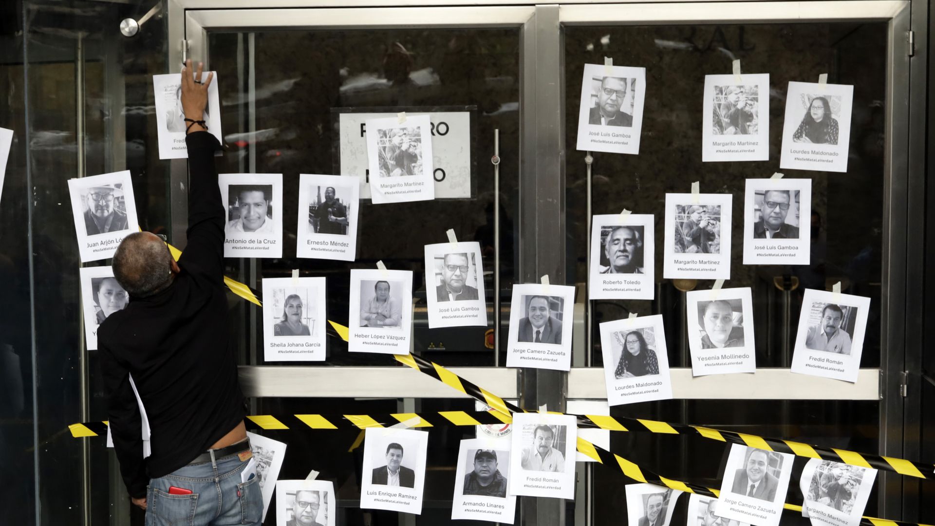 A man puts up a poster of a murdered journalist in Mexico City
