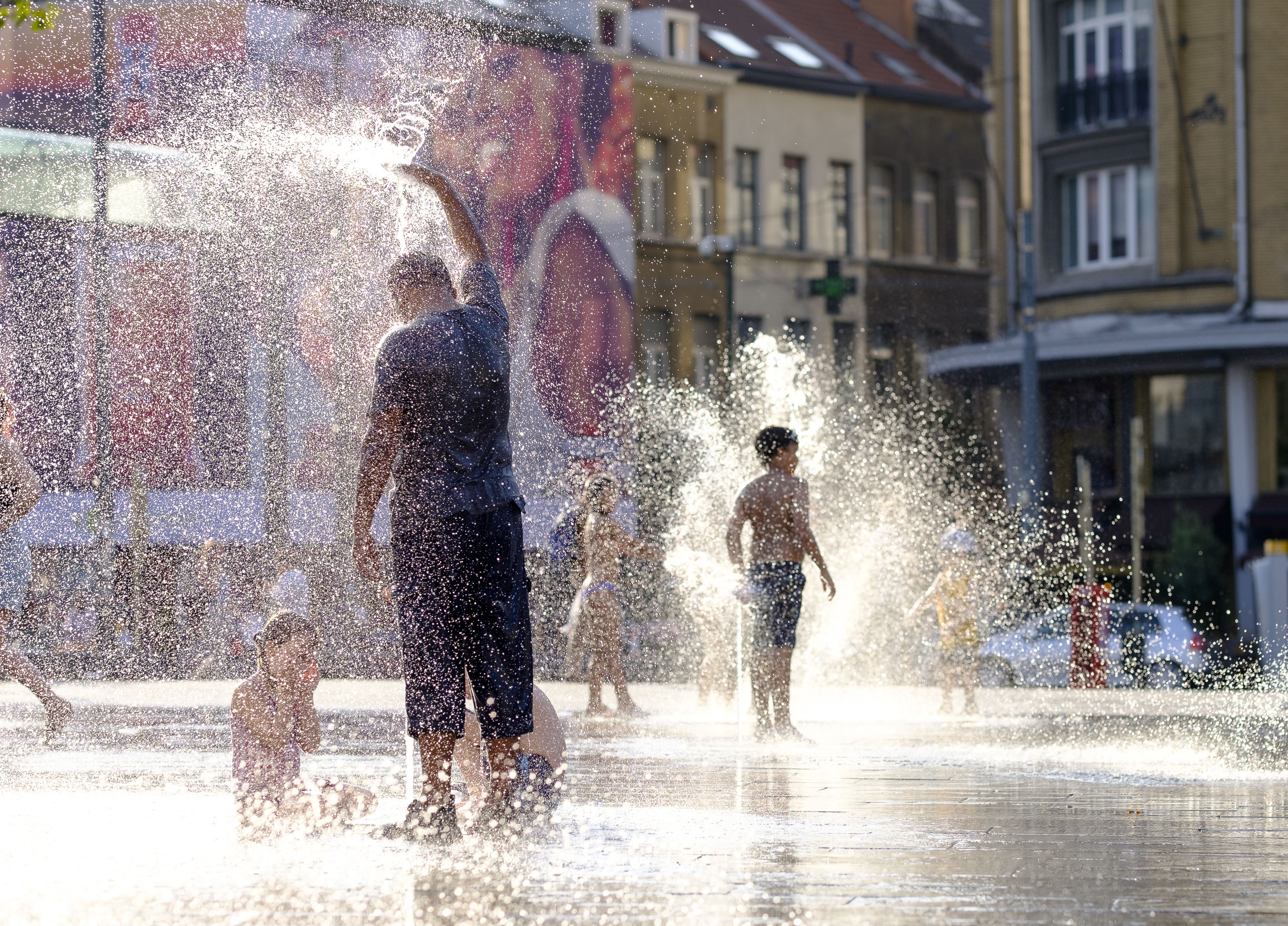  People cool off in the water of a fountain in Place Flagey, Brussels, Belgium