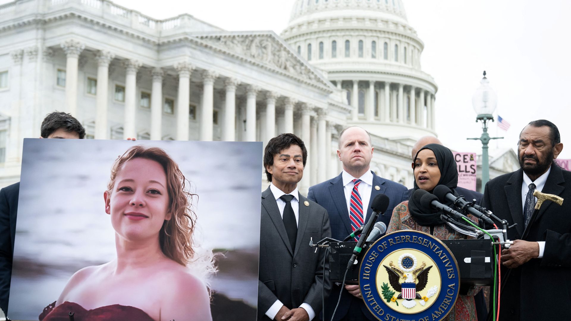 Omar speaking into the microphone outside of the Capitol, while several other Democratic lawmakers stand beside her an an image of Renee Nicole Good