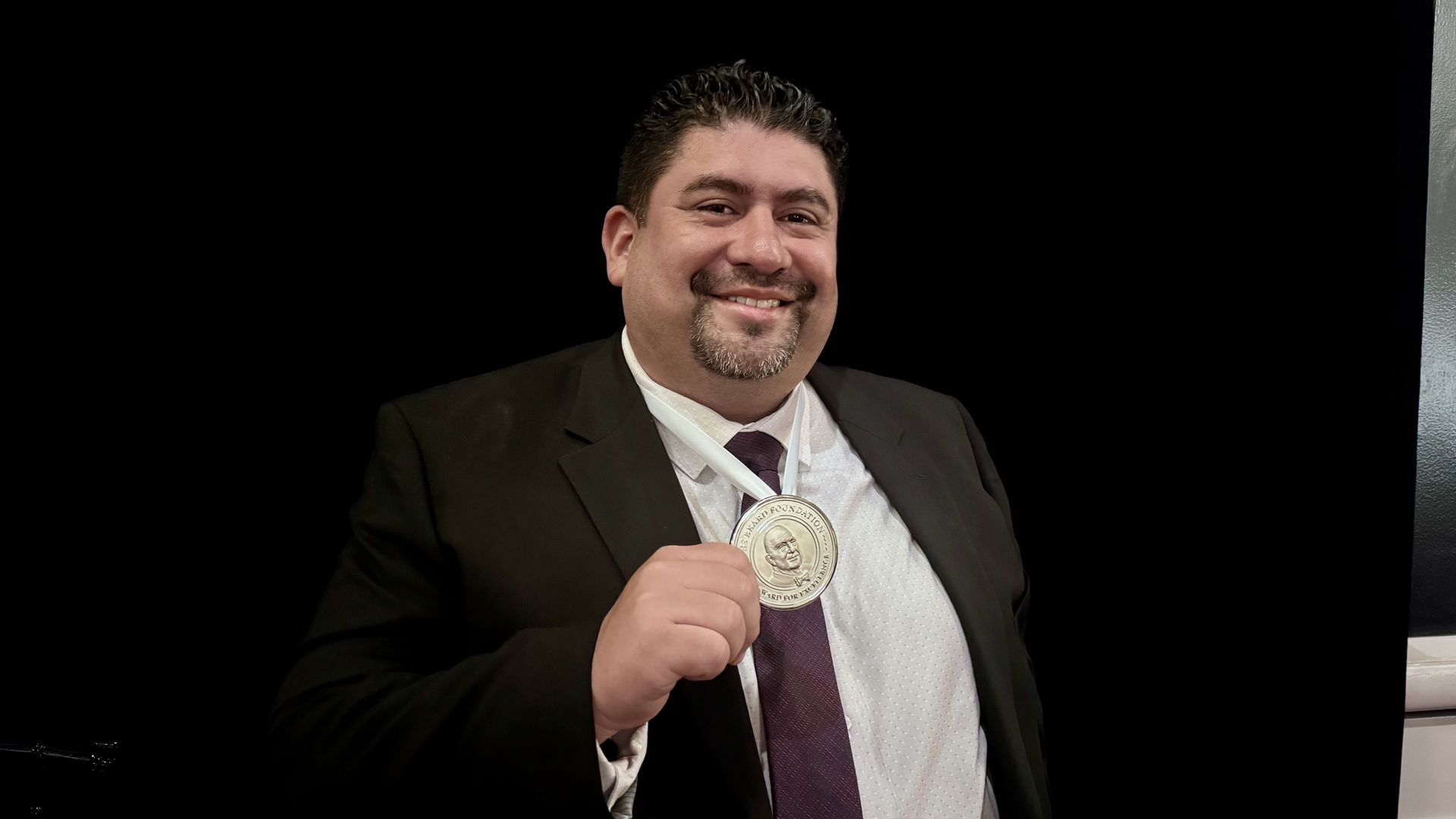 Photo of a chef holding a James Beard medal.