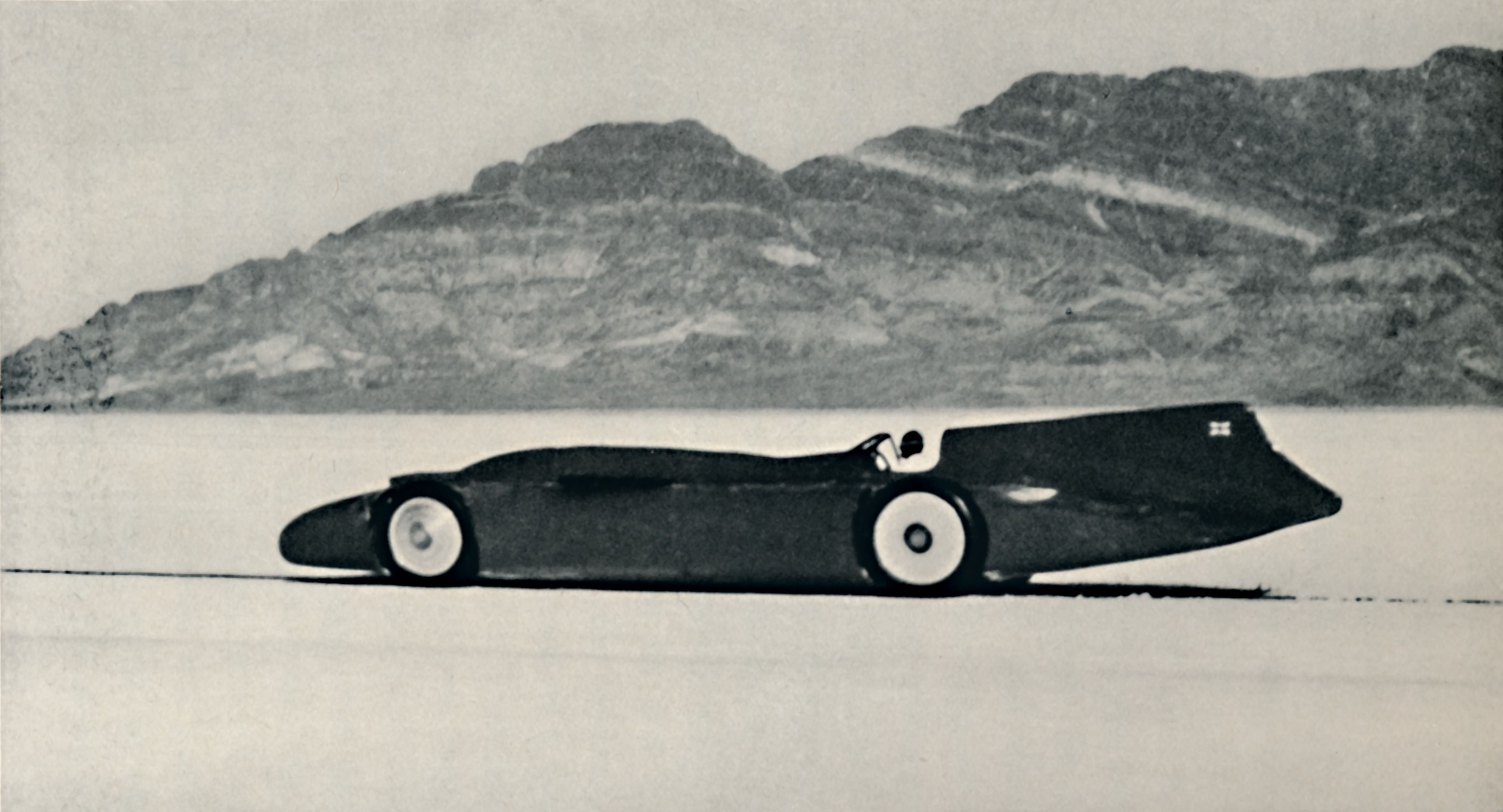 A race car drives by a mountain on the Bonneville Salt Flats, 1935.