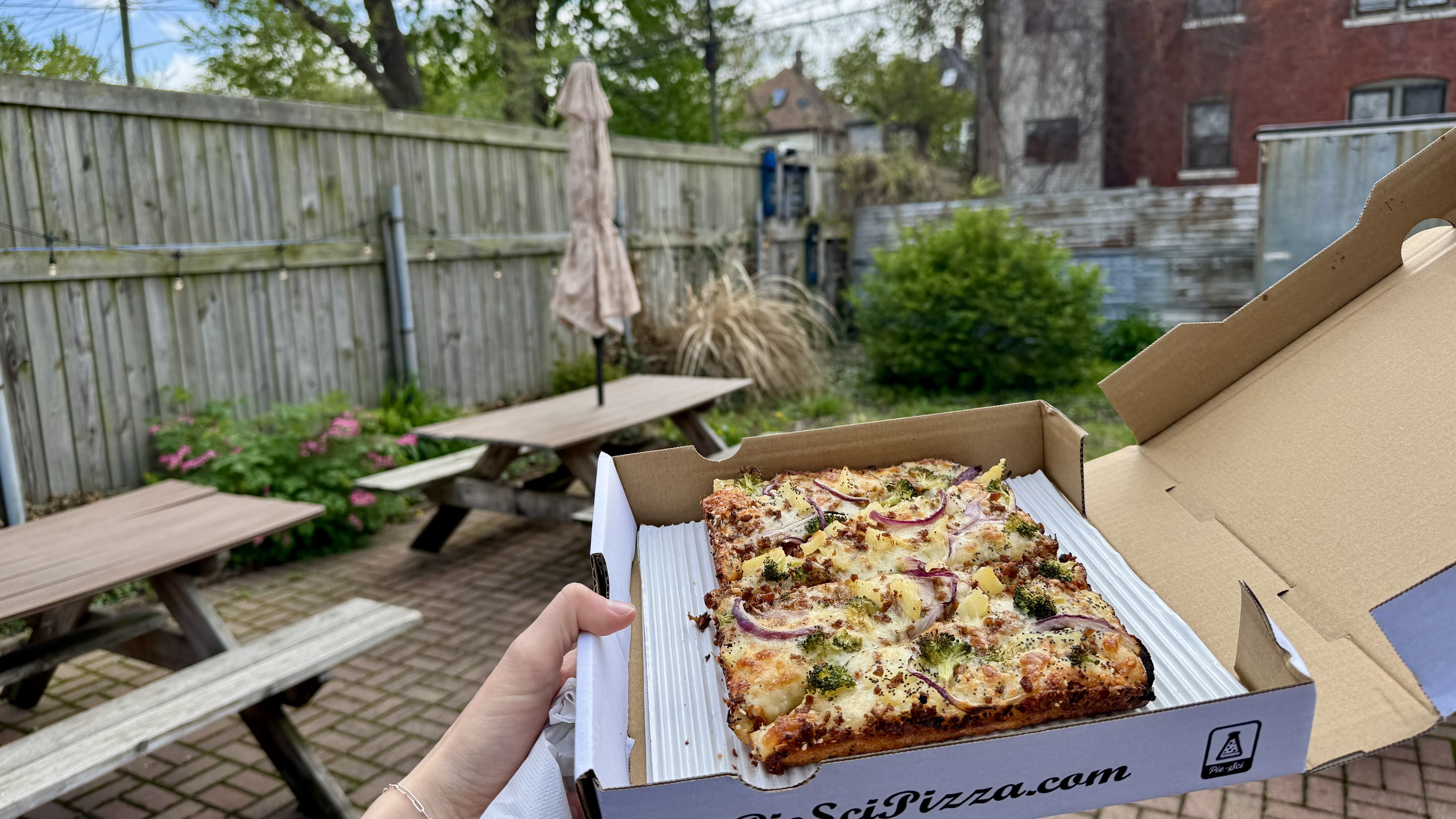 Pizza with a green and brick patio in the background 