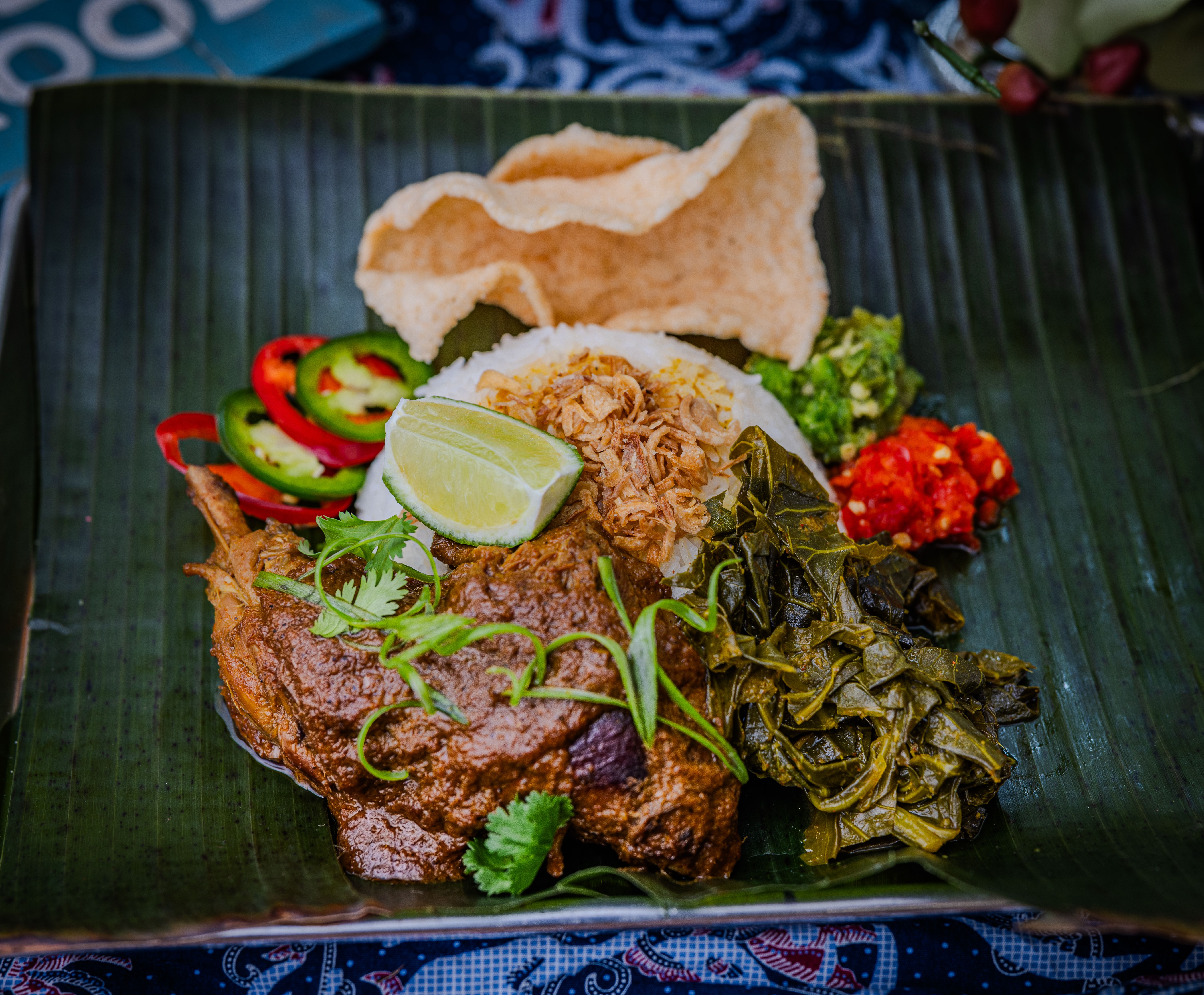 banana leaf topped with rice, stew and garnishes 