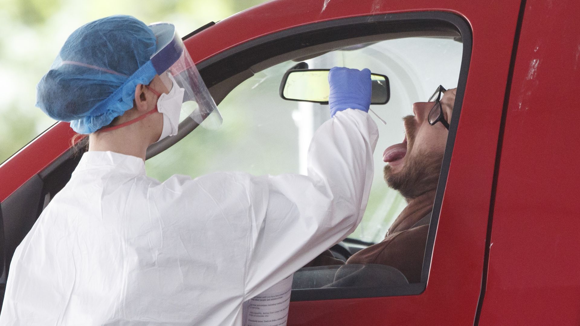 A medical worker takes a swab sample at a COVID-19 drive-thru testing site