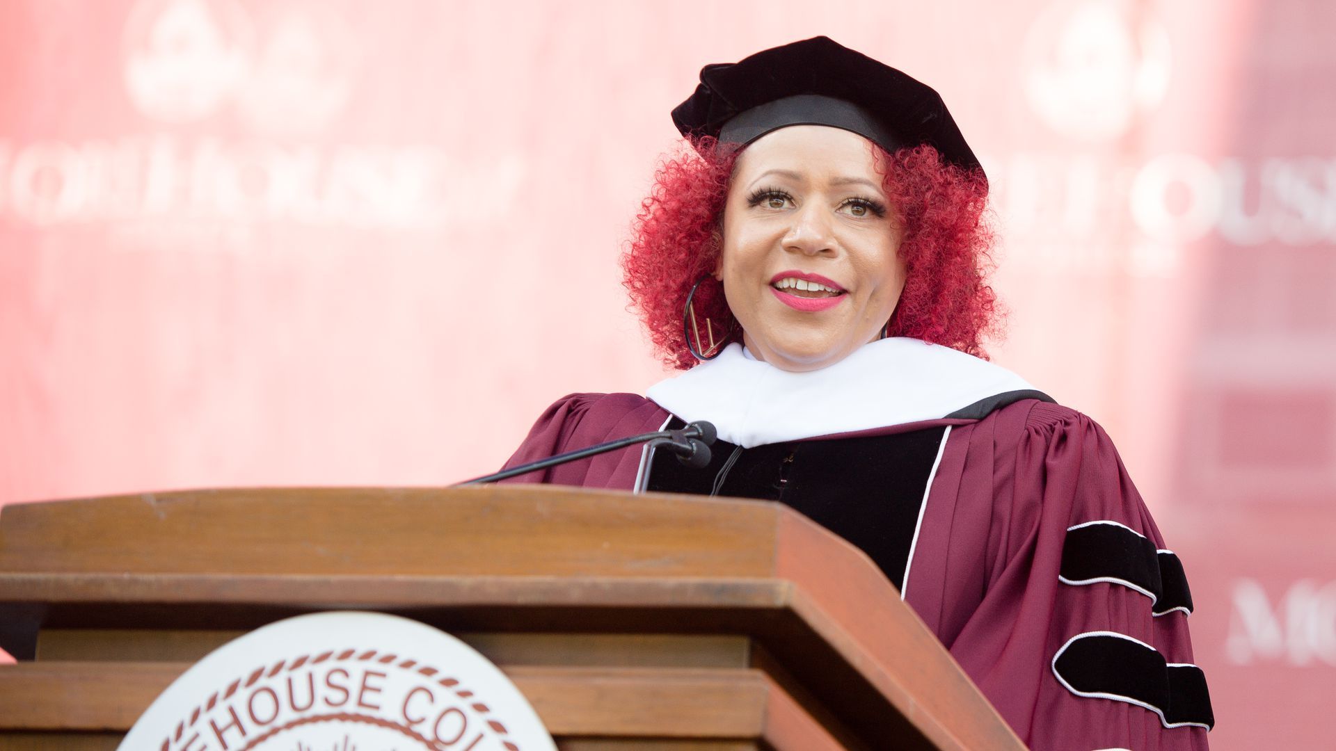 Journalist Nikole Hannah-Jones wears a cap and gown and speaks at a podium