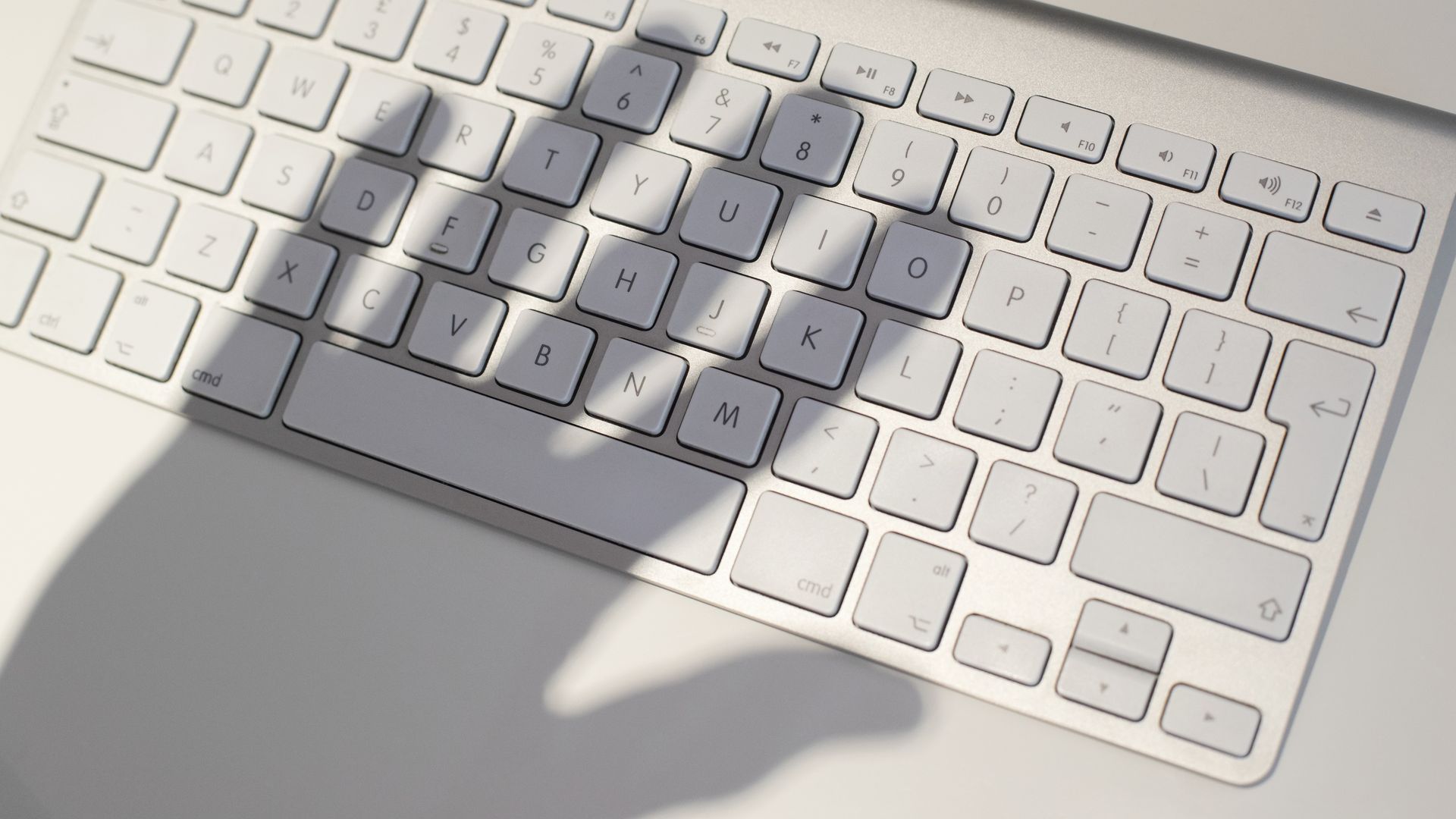 Shadow of a hand looms over a keyboard