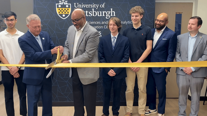 A group of men cut the ribbon on a new AI innovation center. 