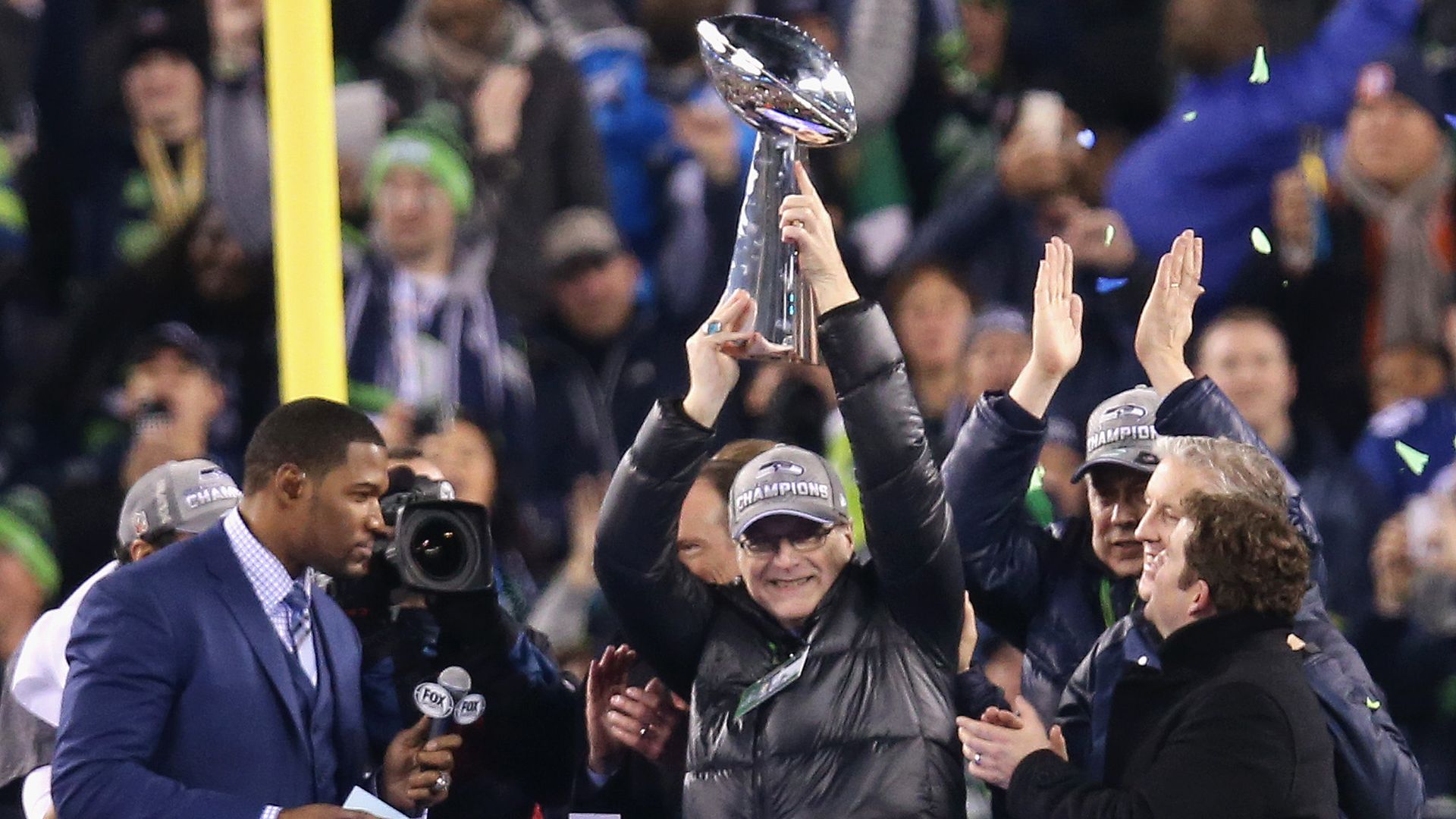 Paul Allen holding up a super bowl trophy