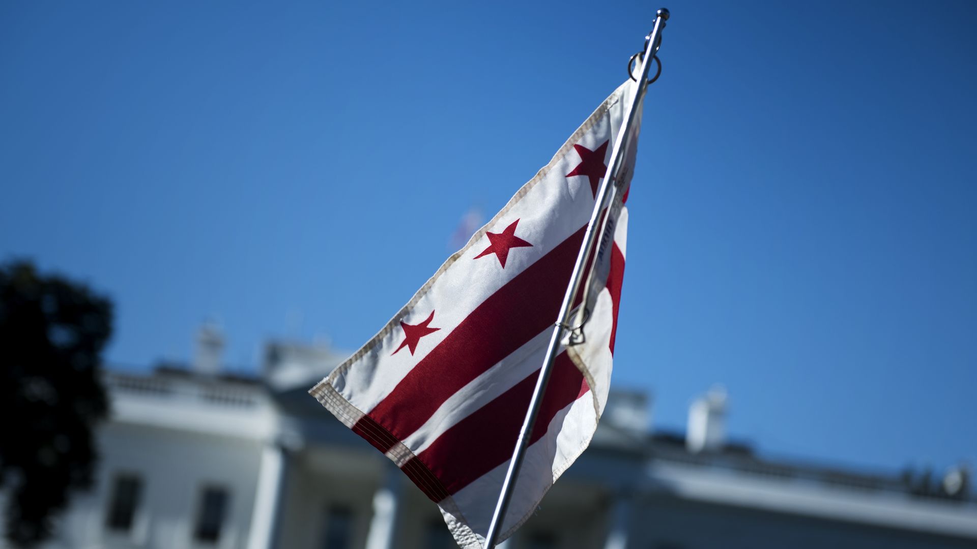 A person holds up a D.C. flag in front of the White House