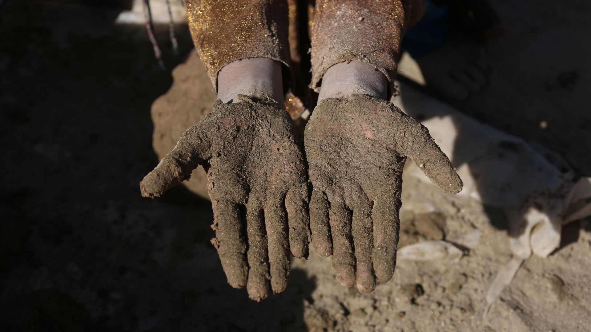 A child shows their dirt covered hands