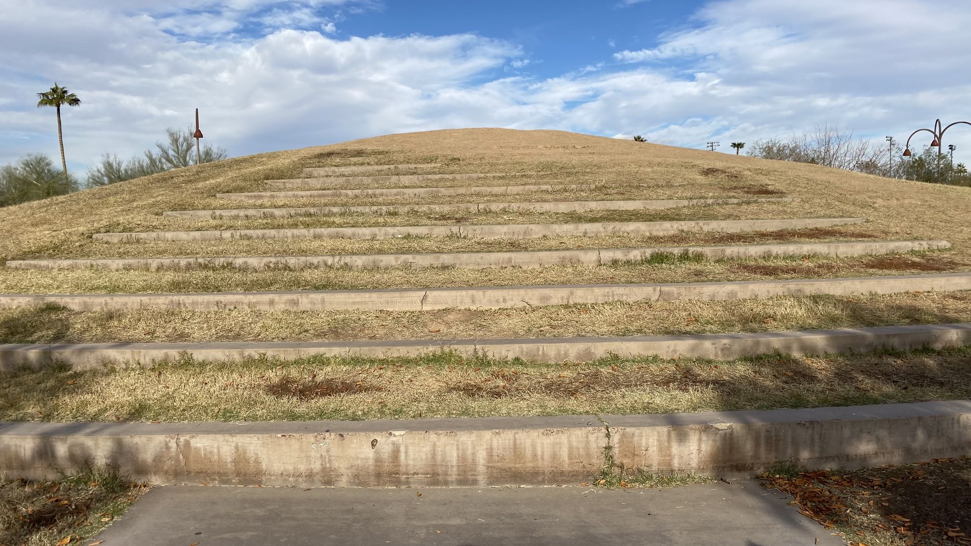 Long concrete steps leading to the top of a small hill covered in dead grass.