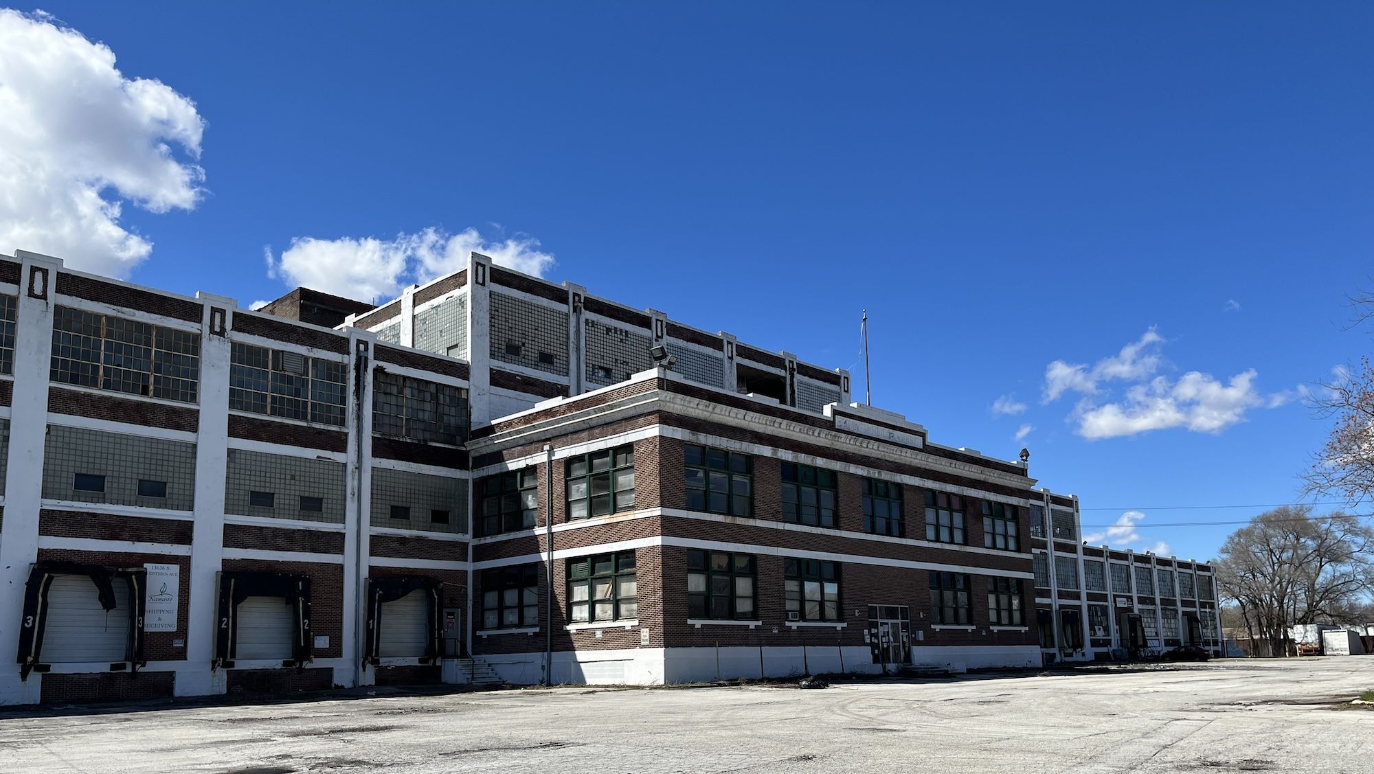 Large, boxy brown brick and white building and empty parking lot.