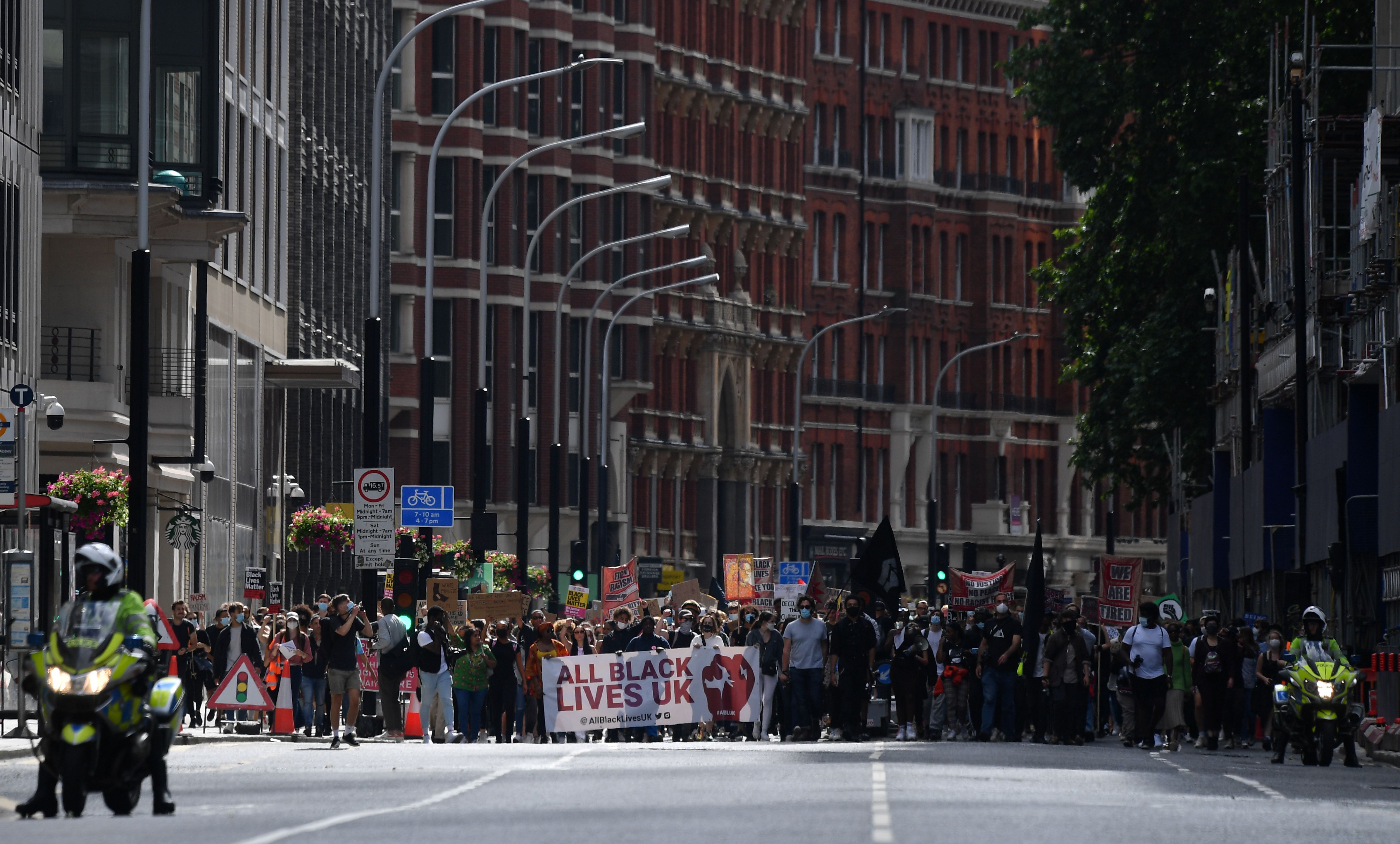 Protesters hold placards as they march through London towards Parliament Square in support of the Black Lives Matter movement in London on July 5, 2020