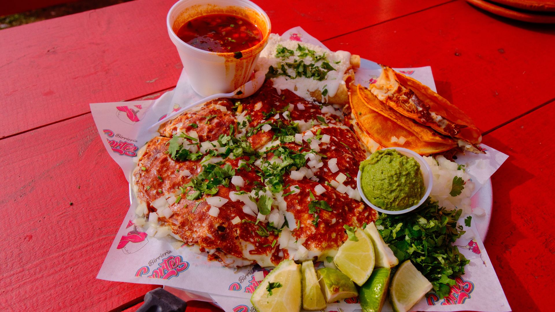 Two tacos, a quesadilla and toppings on a plate