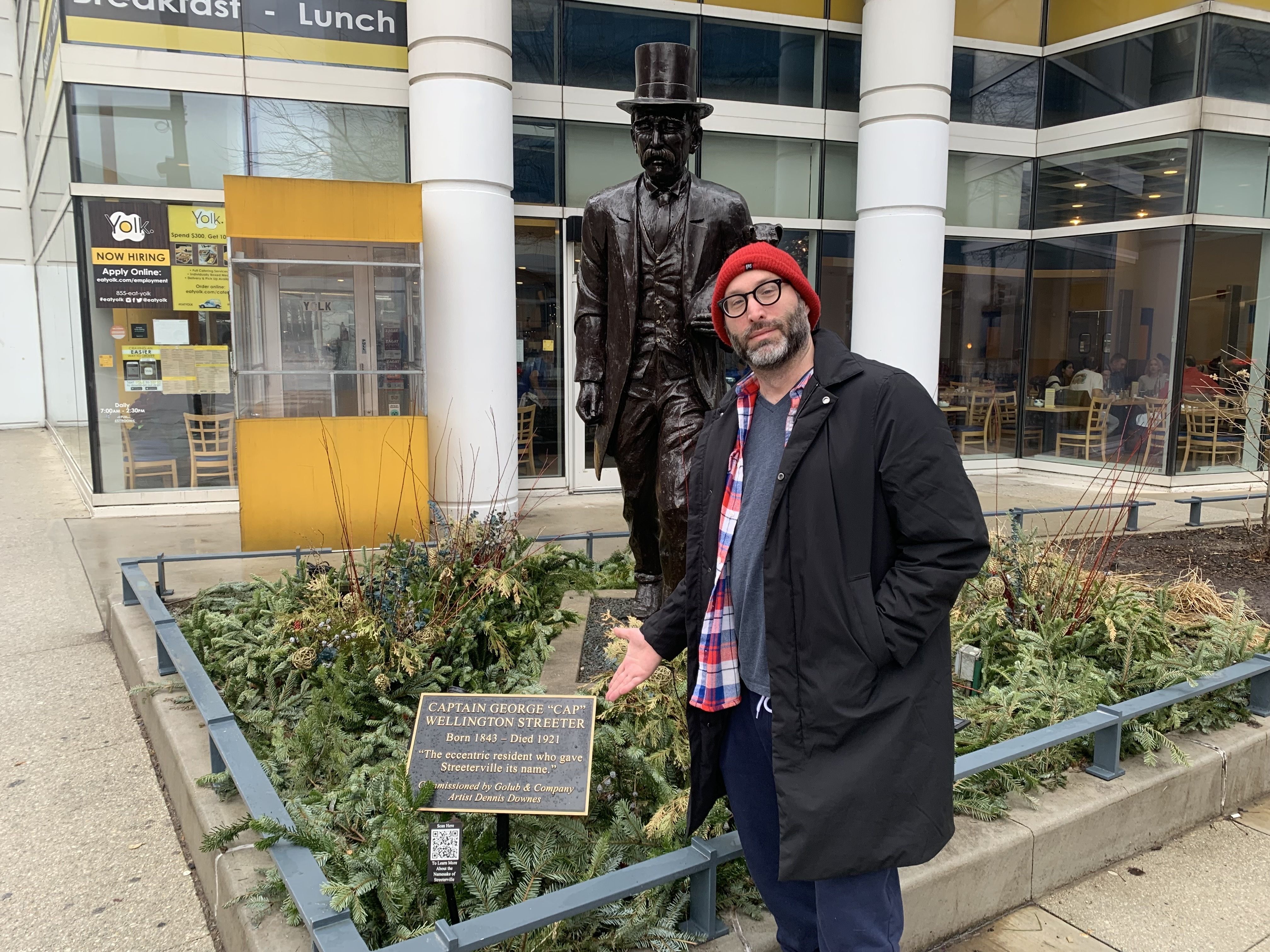 Photo of a man standing next to a statue 