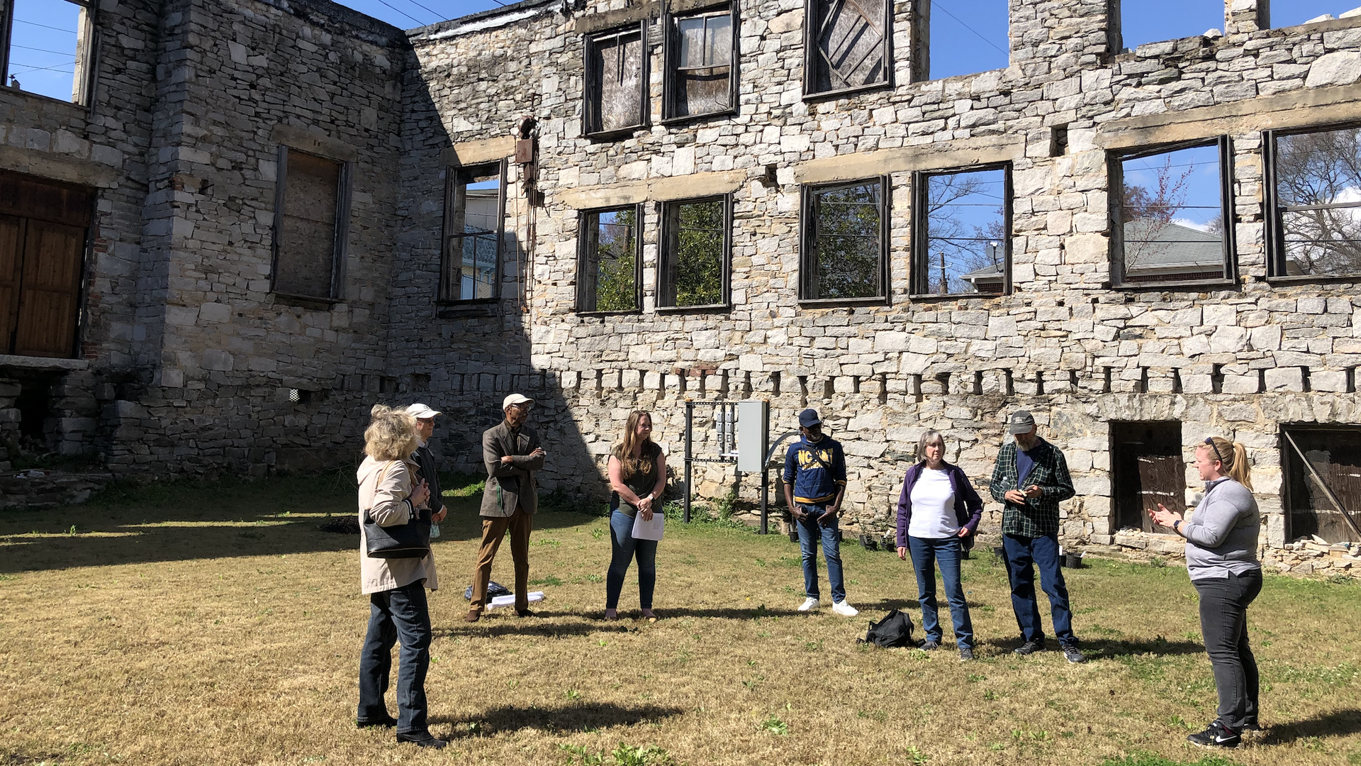A group of people stand in the middle of a historic stone structure with no windows or a roof