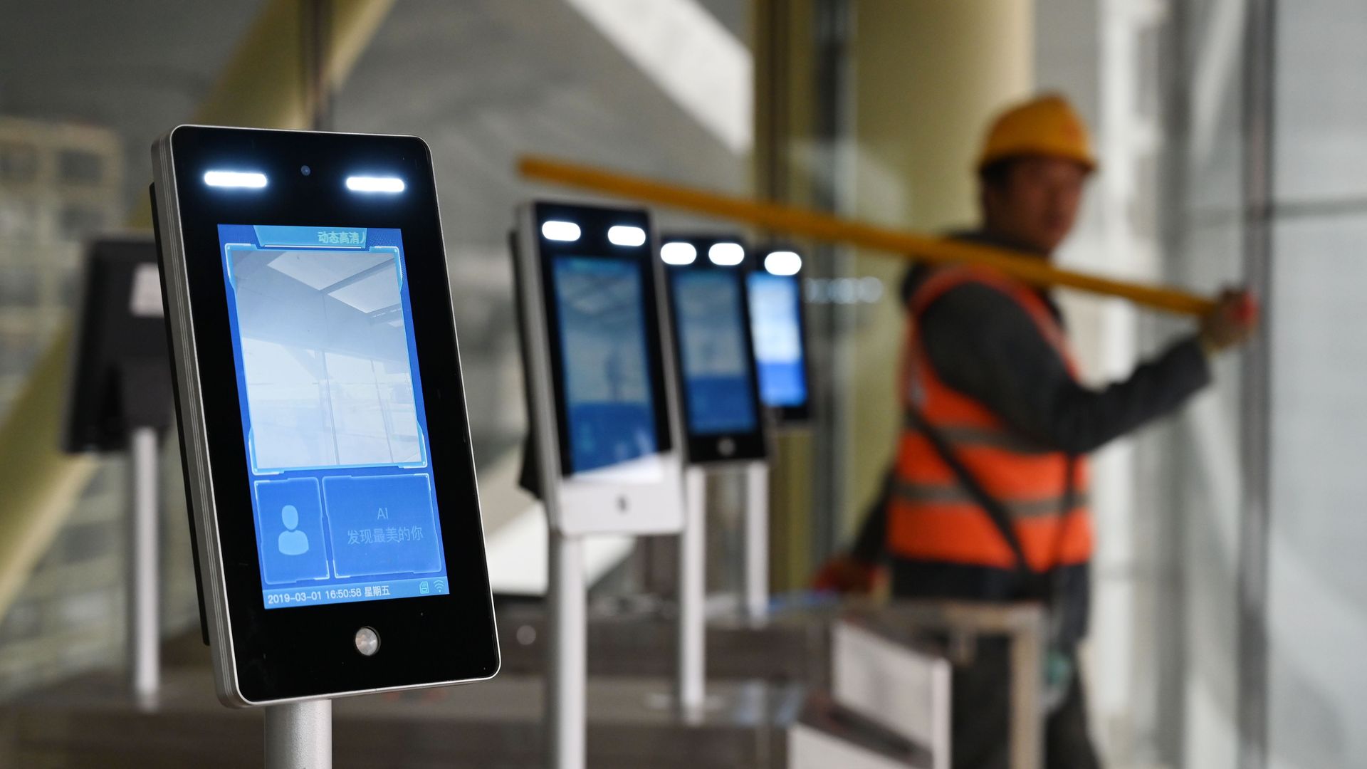 A line of high-tech screens with a construction worker in the background