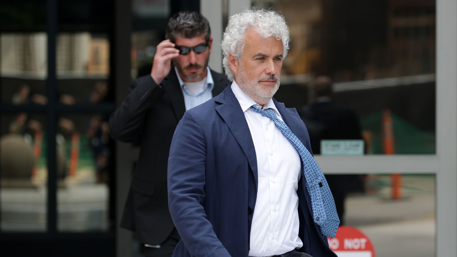 Jeff Zients, wearing a blue suit, blue tie and white shirt, walks.